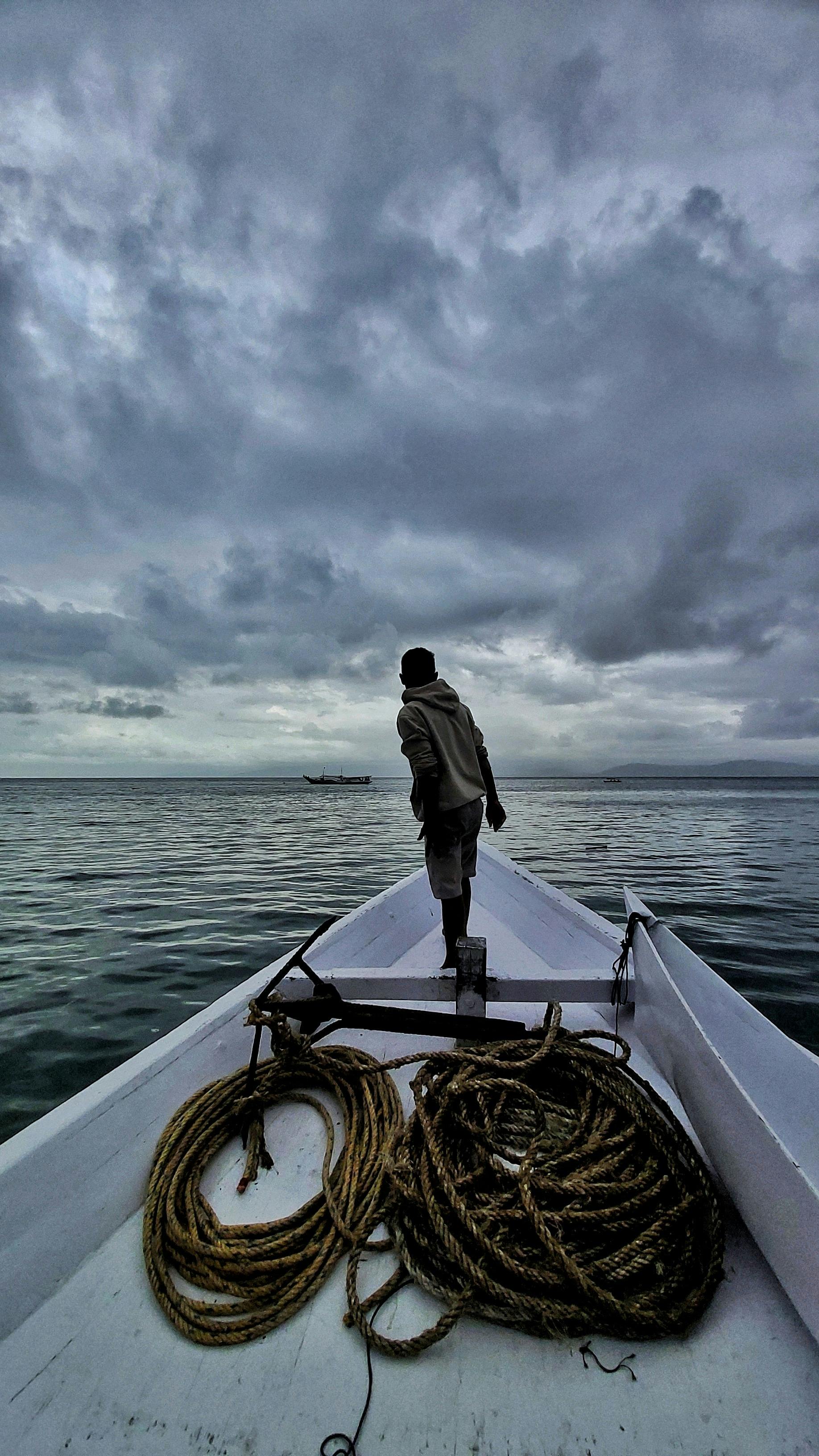 Fisherman on Fishing Boat Under Cloudy Sky