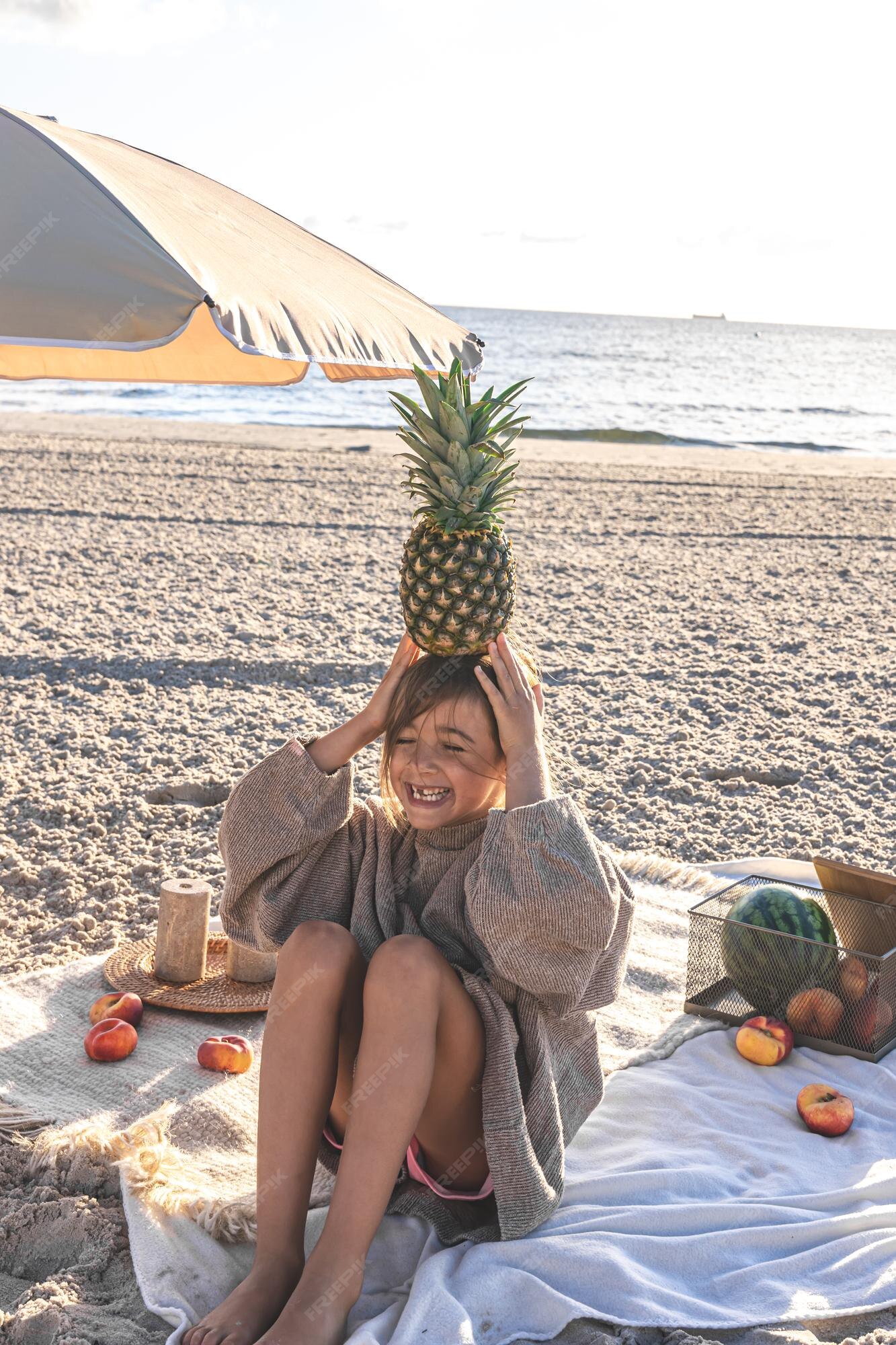 Girl Balancing Pineapple on Beach