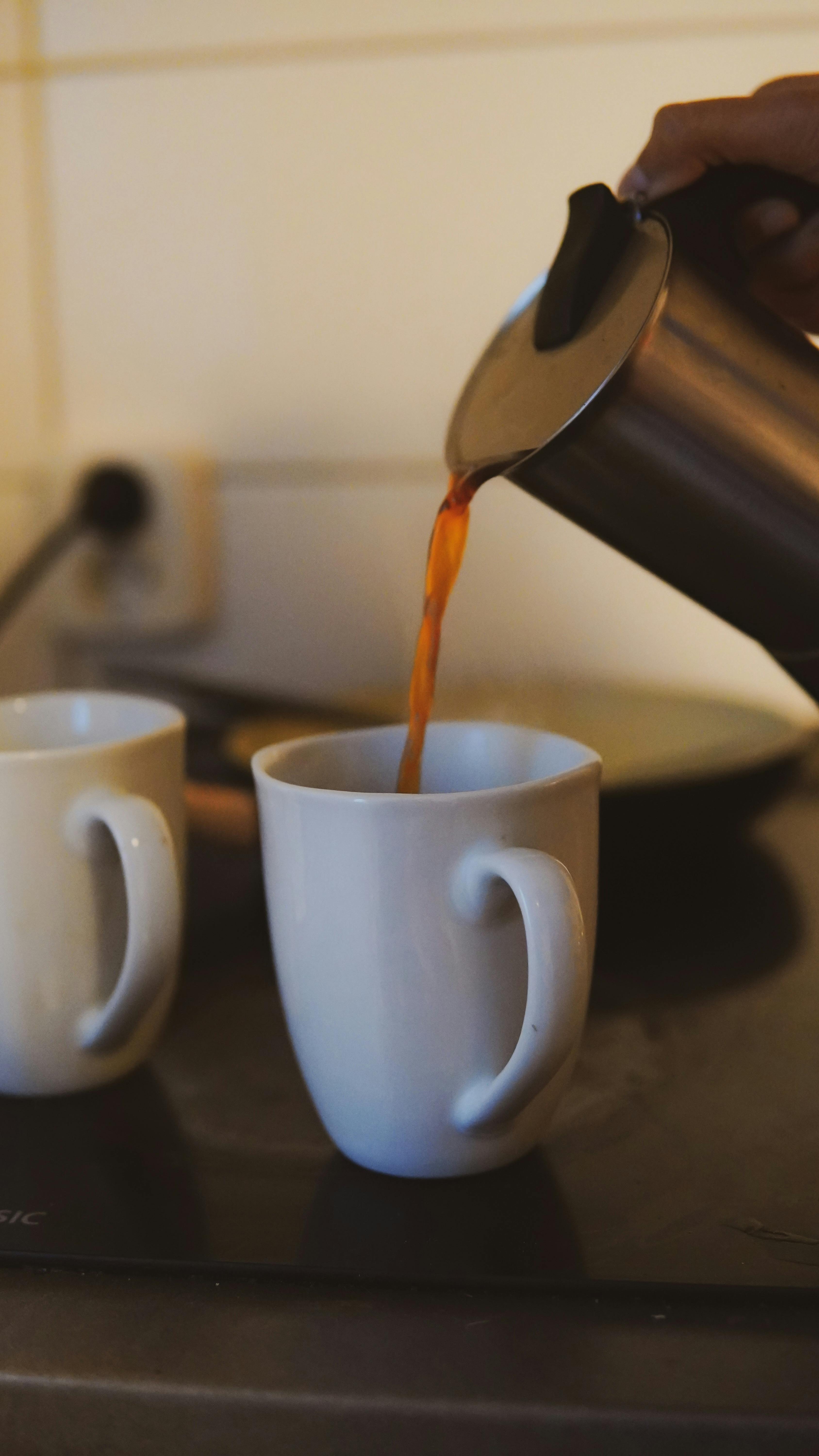 Pouring Coffee Into White Mugs
