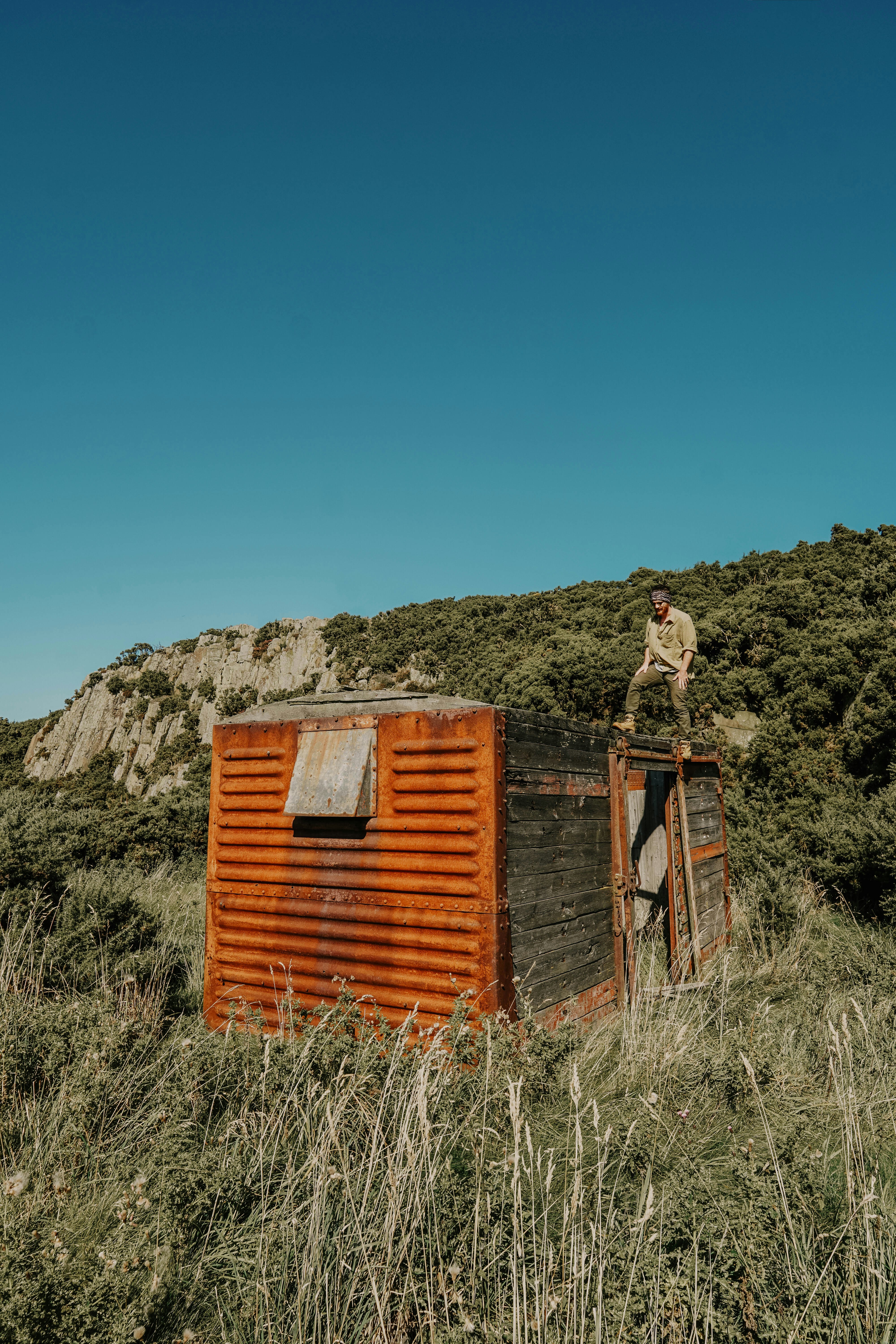 Rusted Hillside Cabin with Man on Top