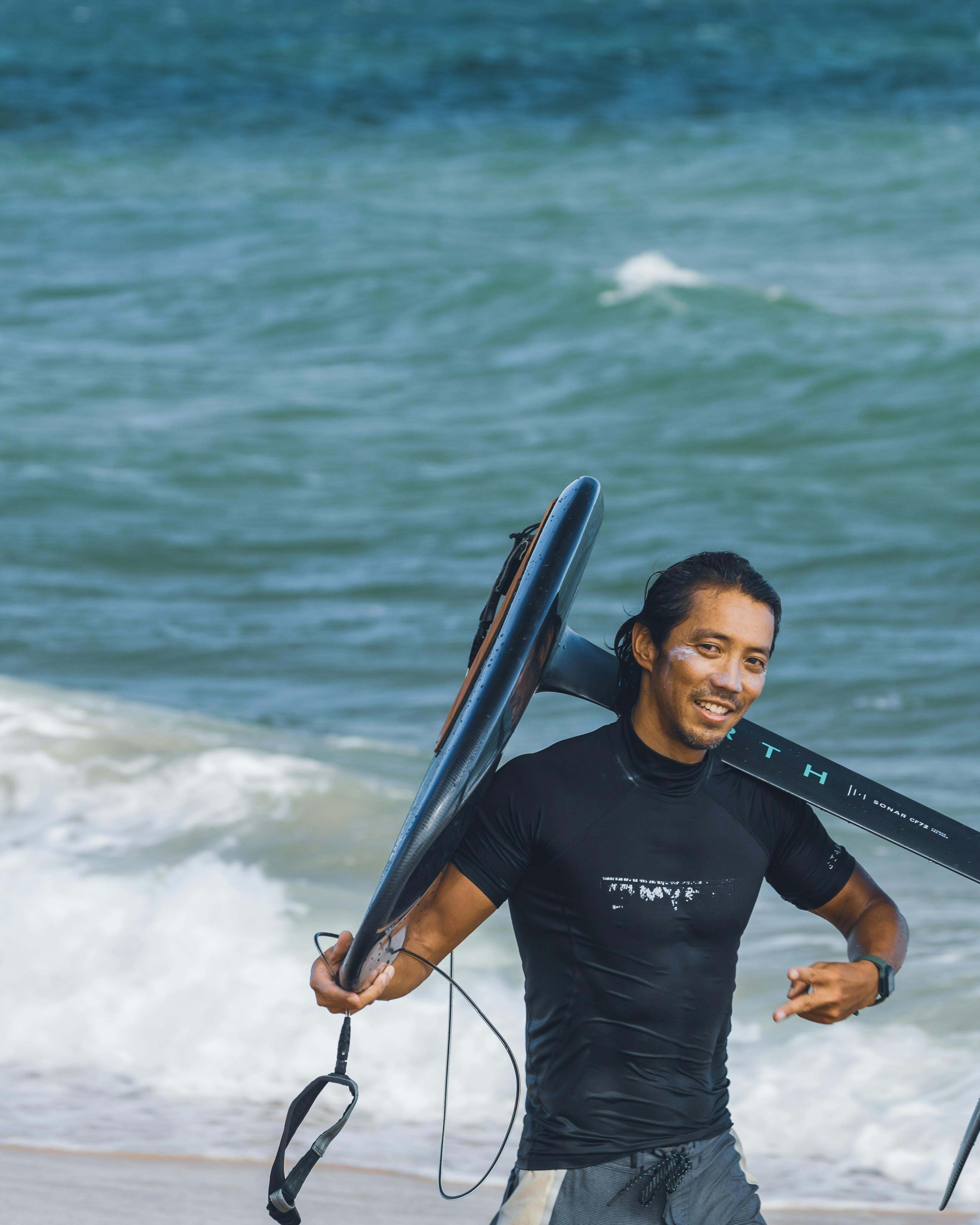 Smiling Surfer Carrying Board on Beach