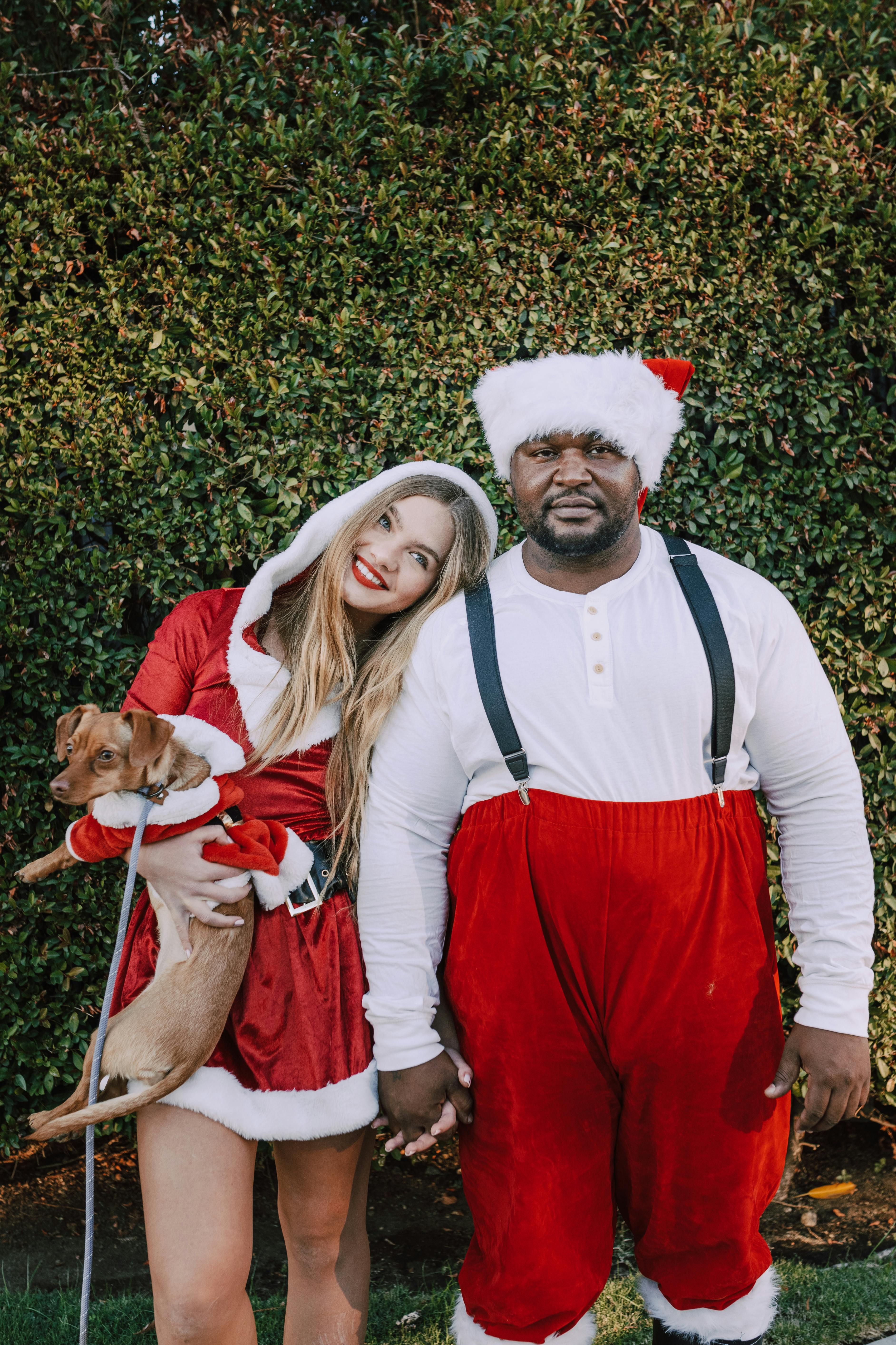 Couple in Christmas Santa Costumes With Dog