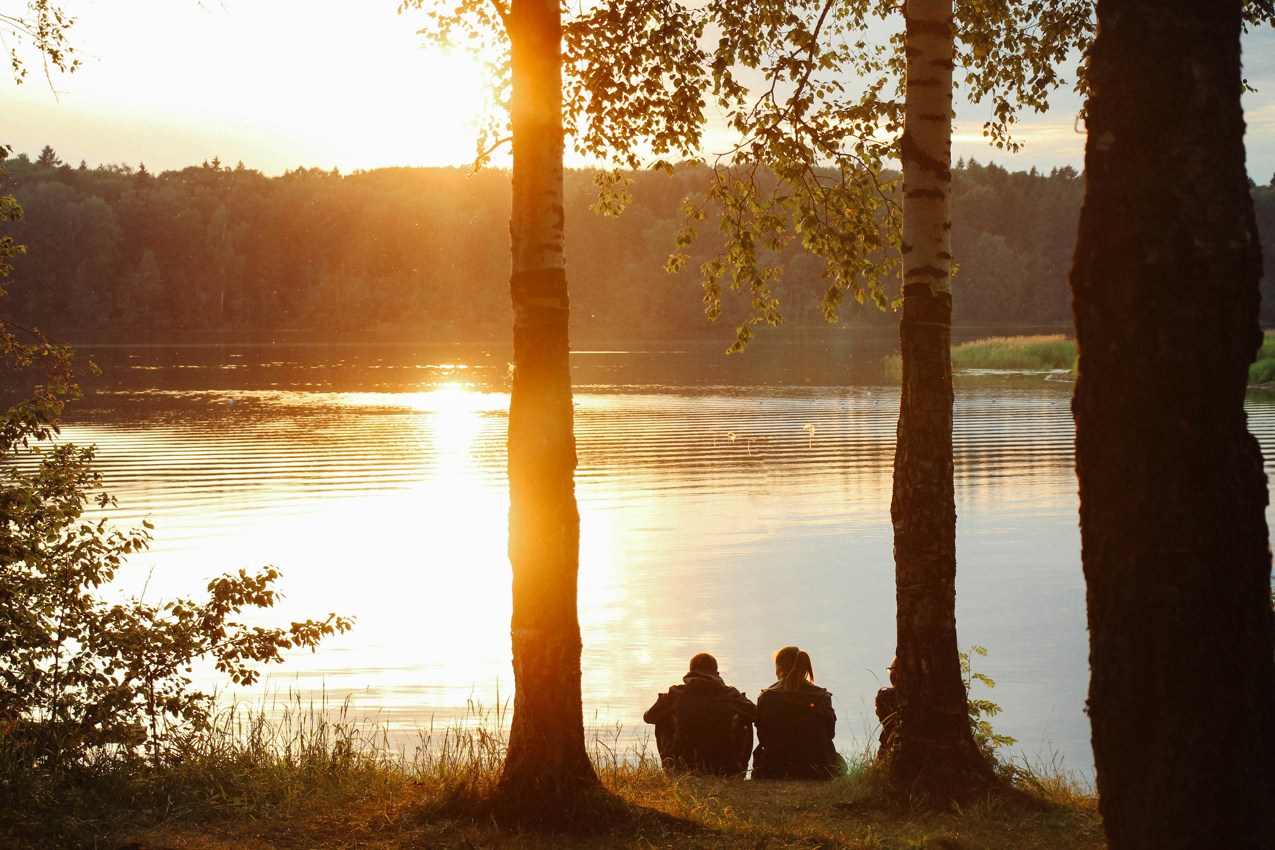 Three People Watching Sunset by Lake