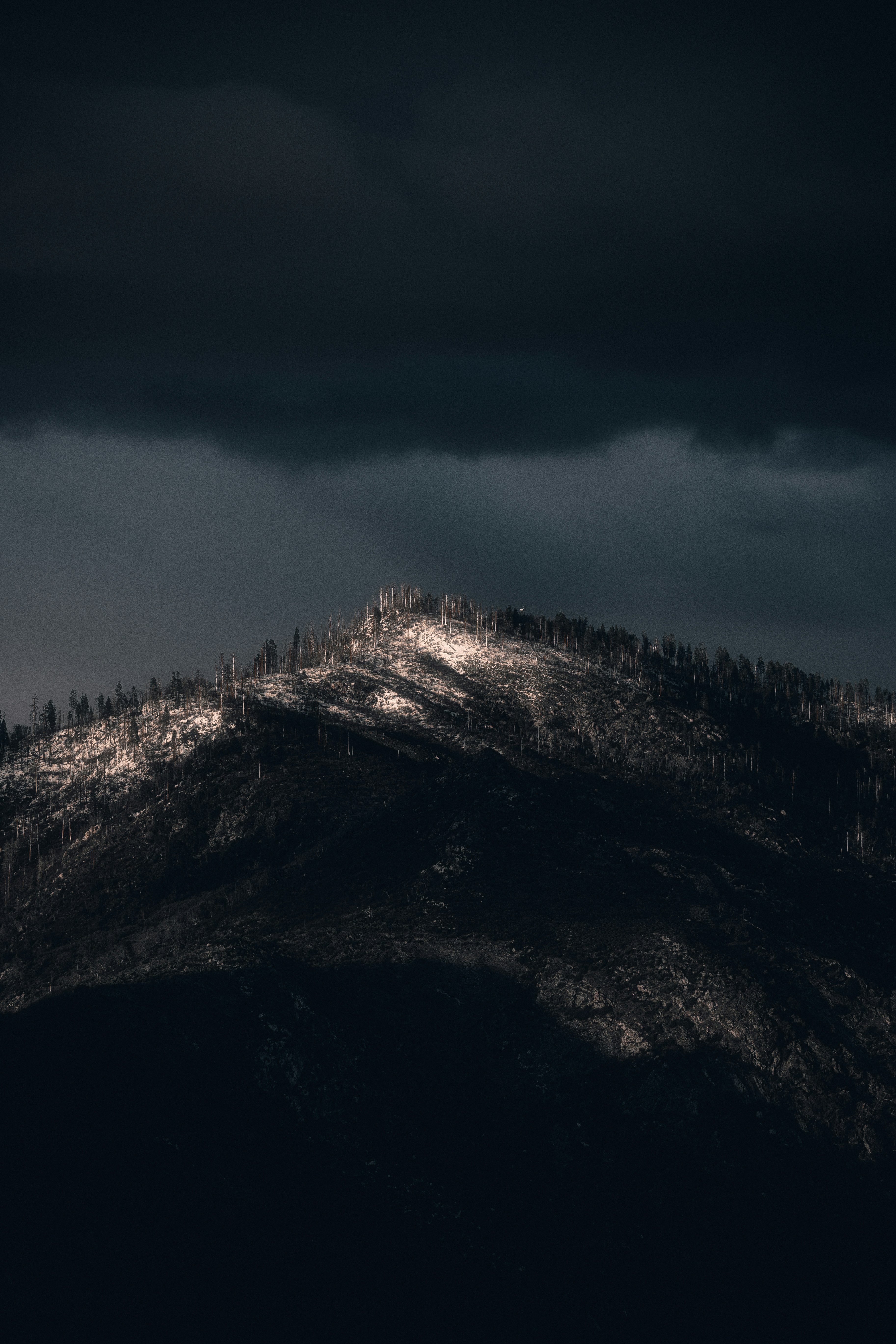 Sunlit Peak Under Dark Sky
