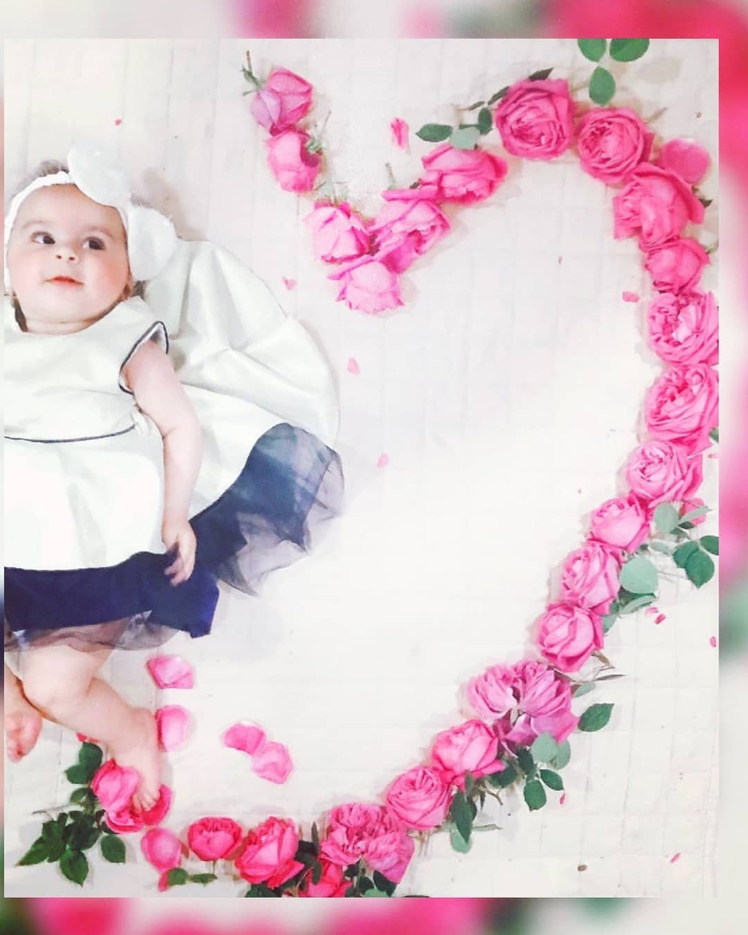 Baby beside heart-shaped pink rose arrangement