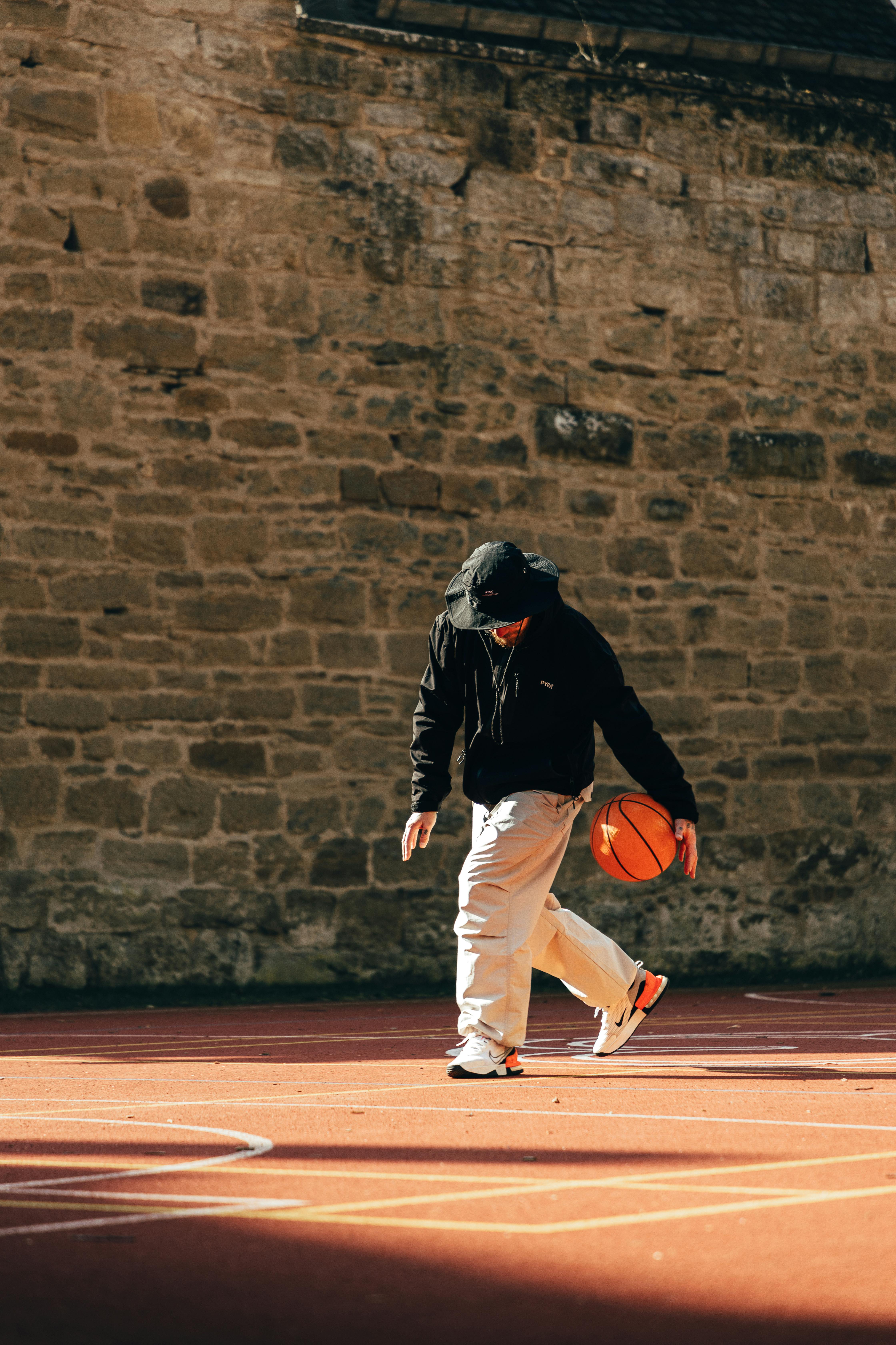 Man Dribbling Basketball on Outdoor Court