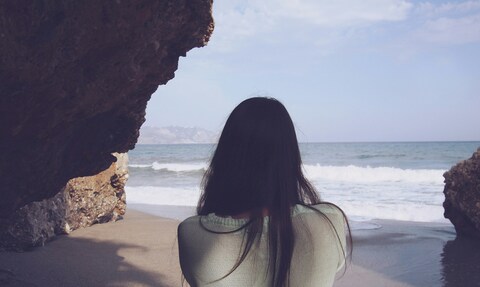 Woman Looking At Sea From Beach Cave