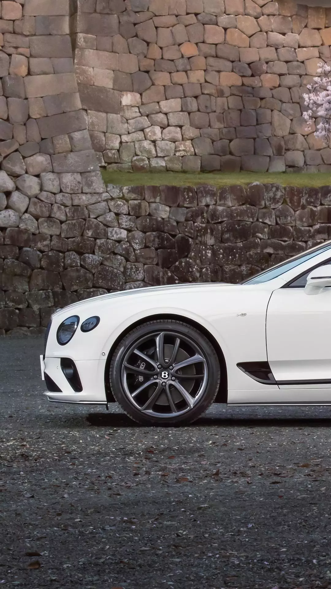 White Bentley Parked by Stone Wall
