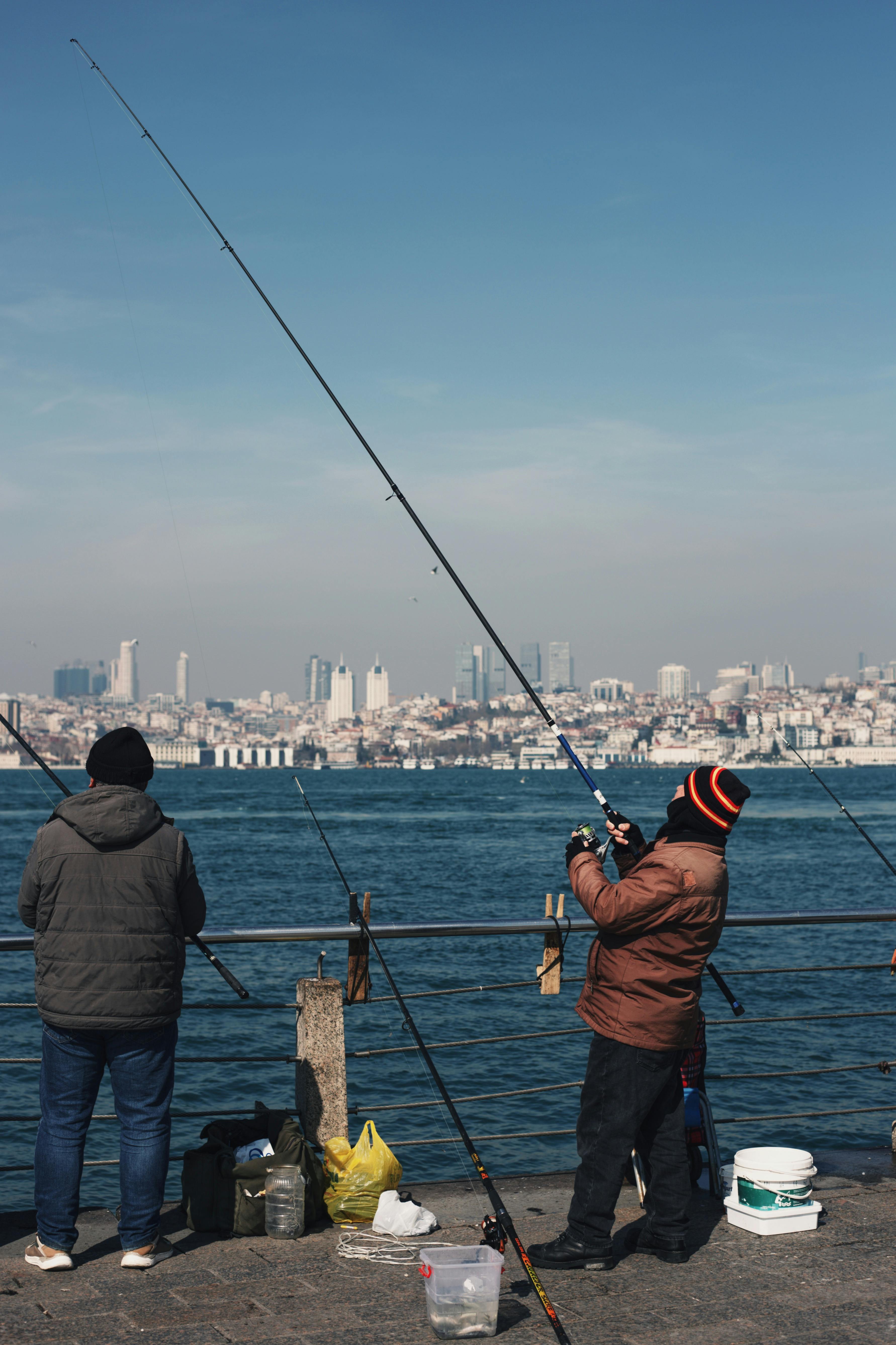 Two Men Fishing on Waterfront Pier