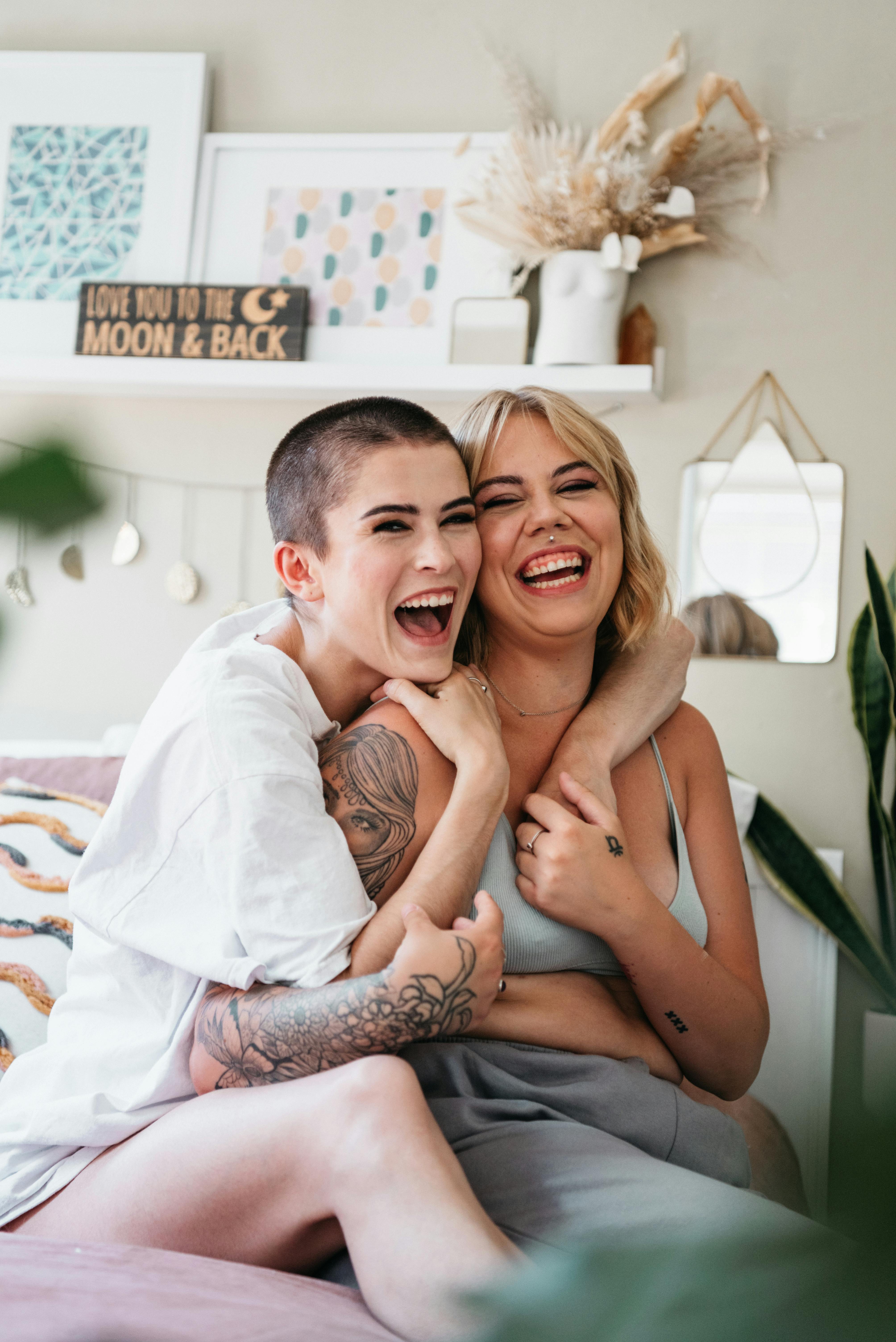 Two Laughing Women Embracing on a Bed