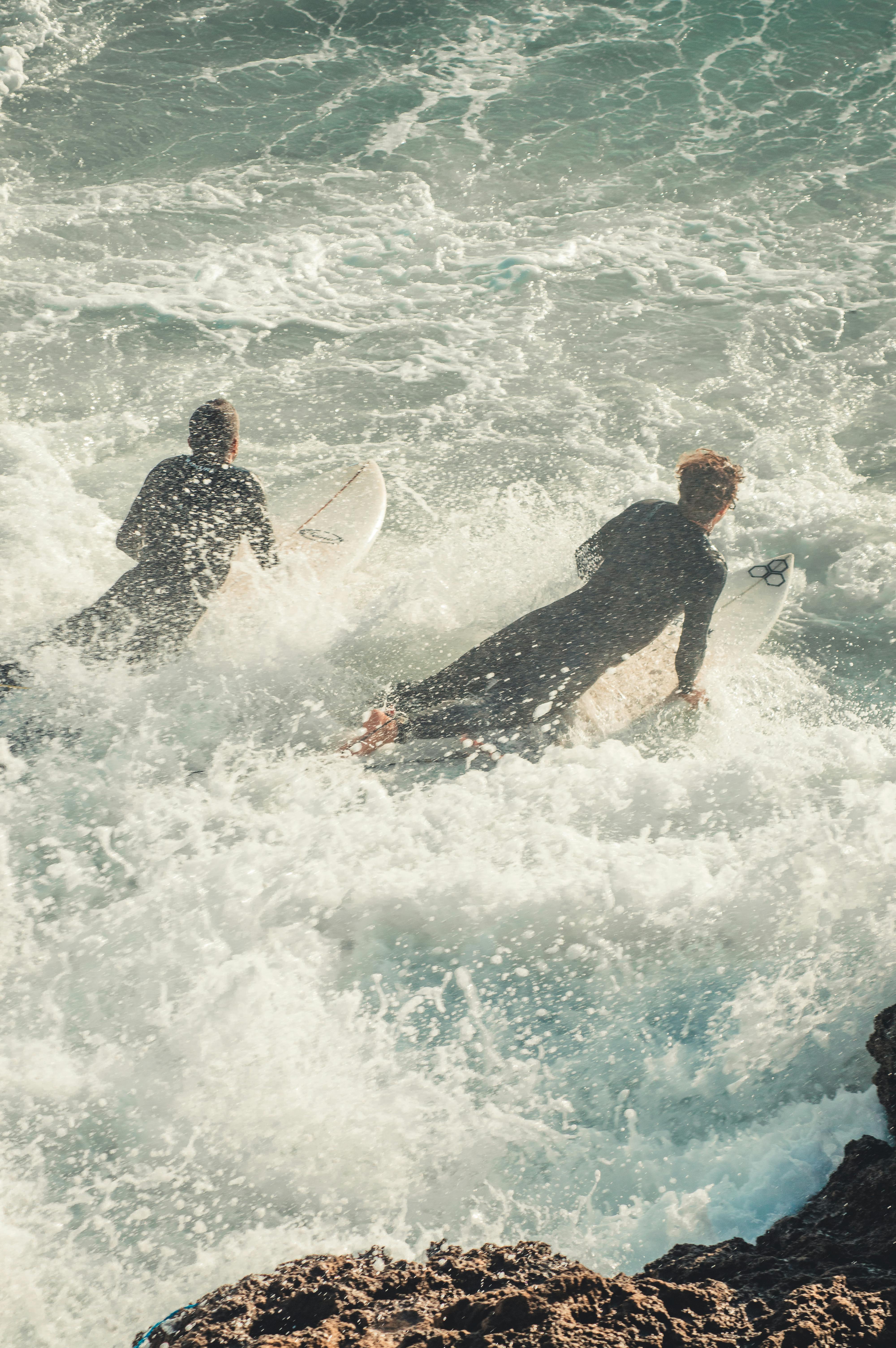 Two Surfers Paddling Through Ocean Waves