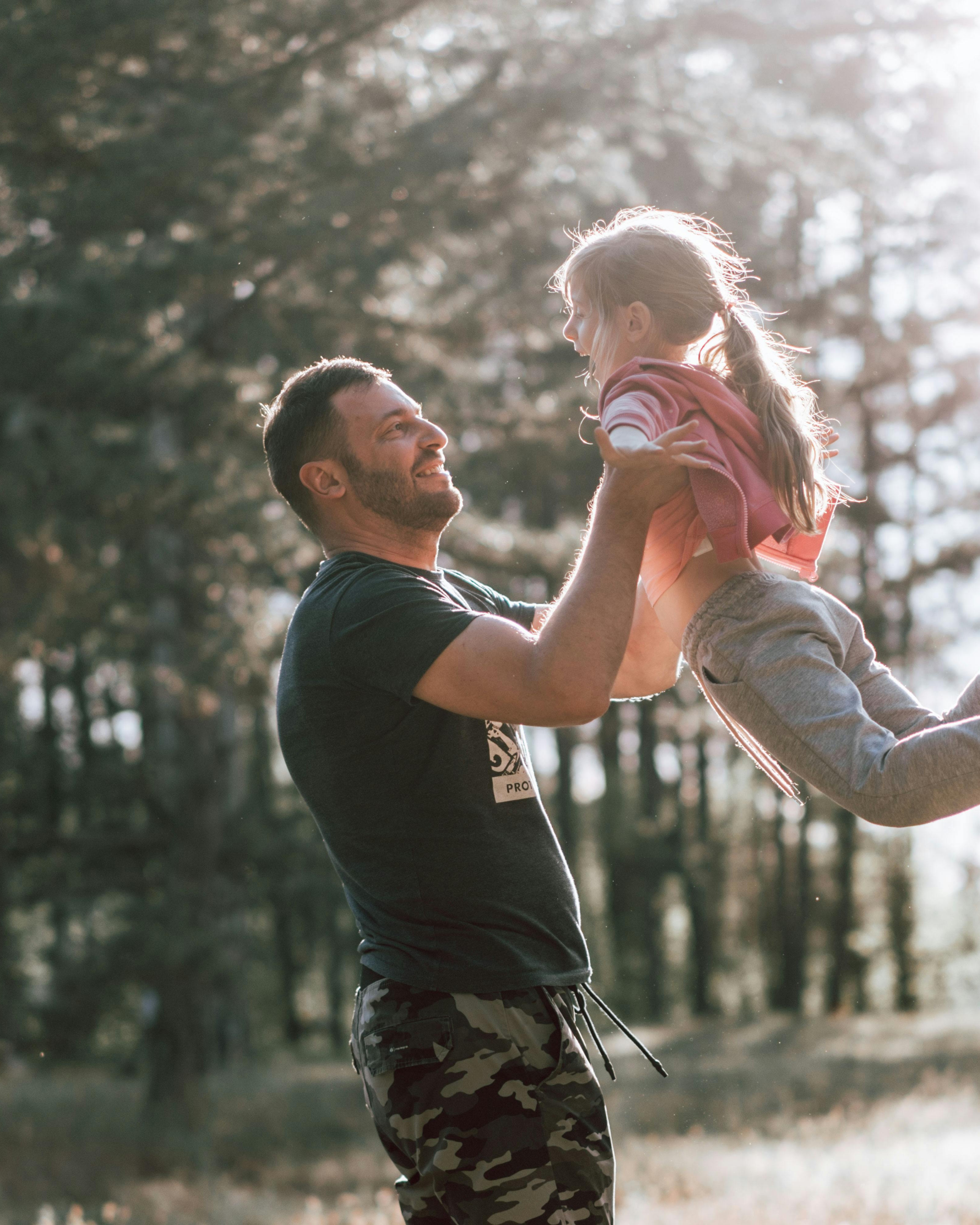 Father Lifting Daughter In Forest
