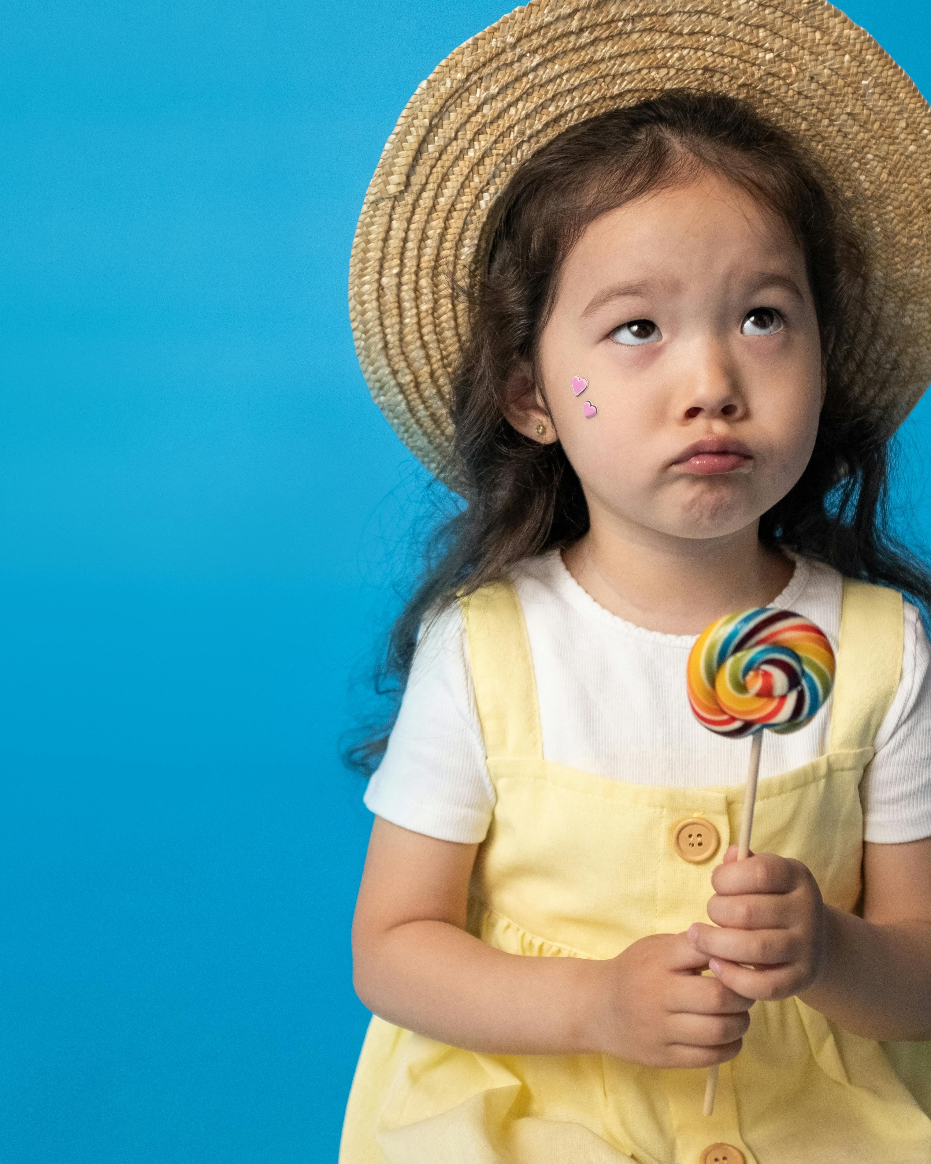 Pouting Little Girl Holding Rainbow Lollipop