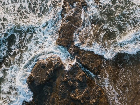 Aerial View of Waves Hitting Coastal Rocks