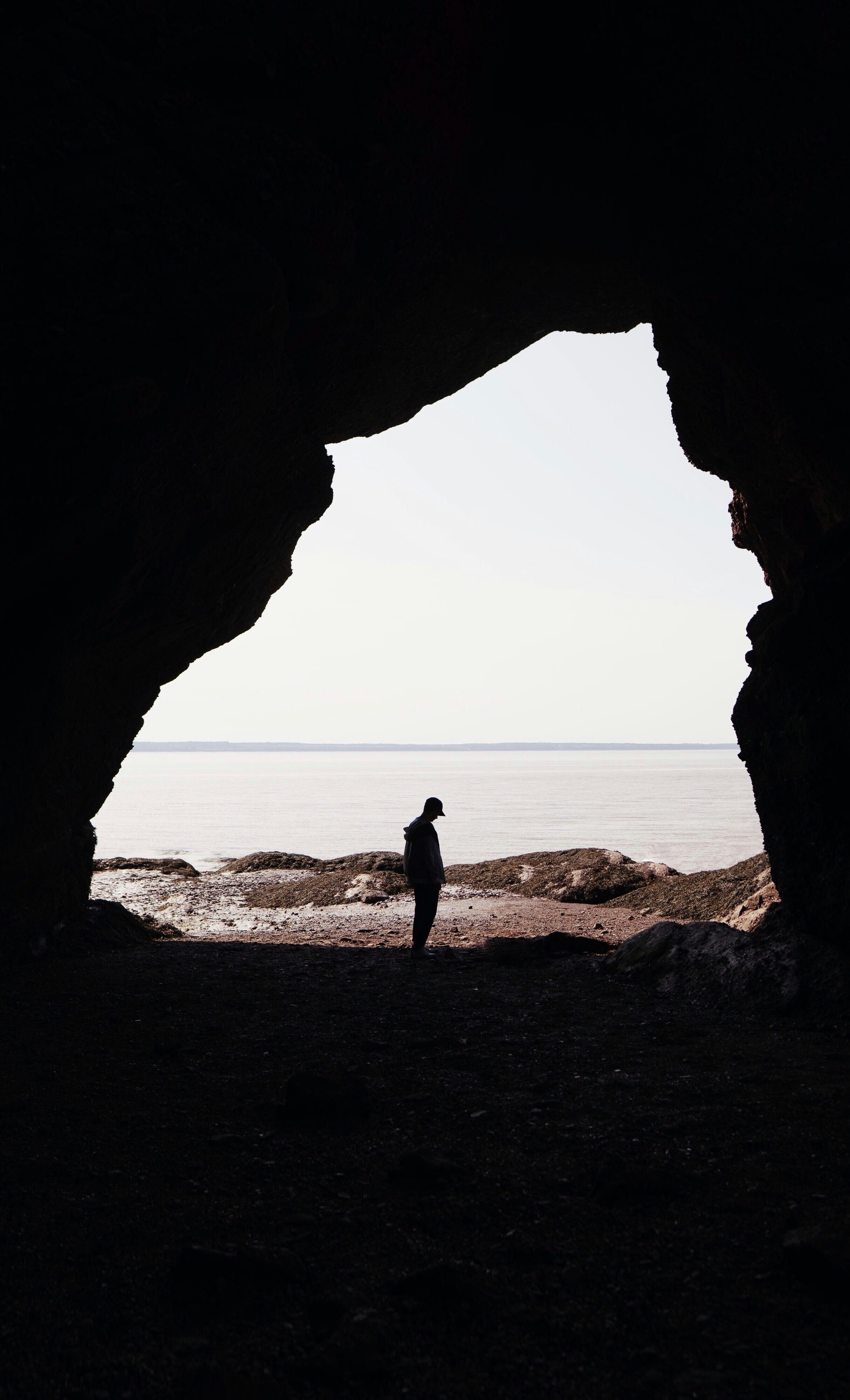 Silhouetted Person in Cave Overlooking Sea