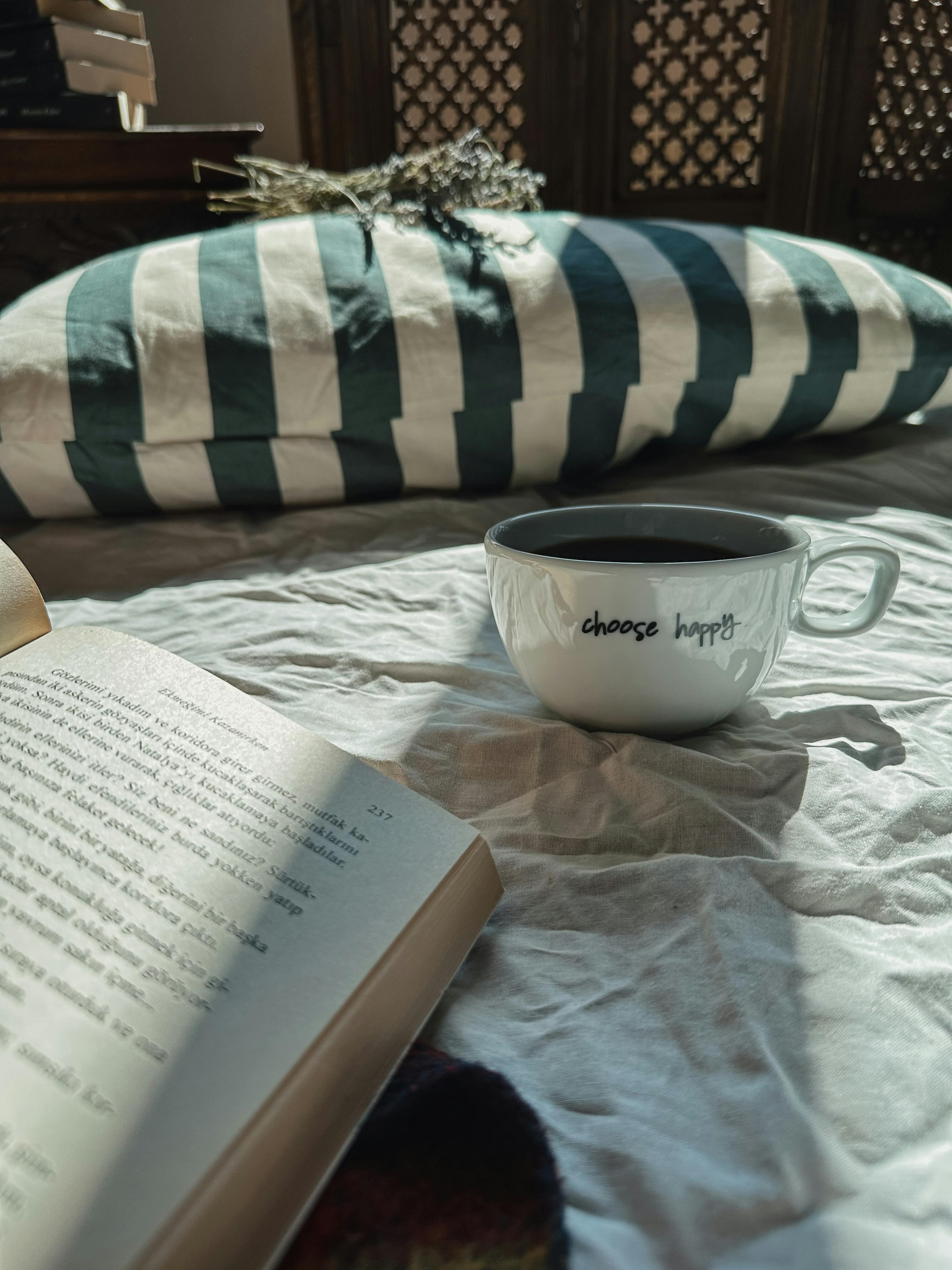 Coffee cup and open book on bed