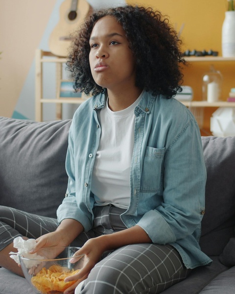 Young Woman Eating Chips on Sofa