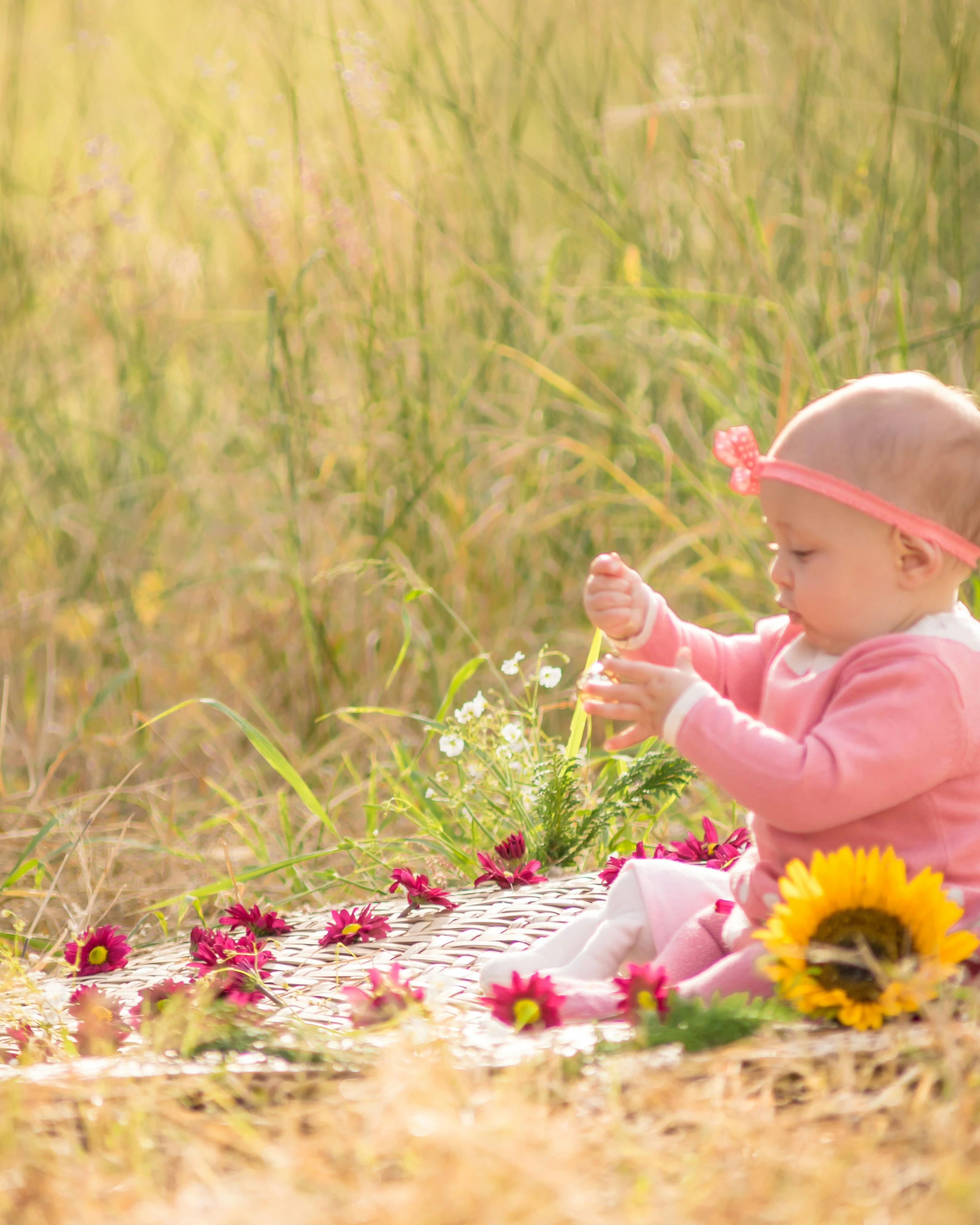 Baby Playing With Flowers in Meadow