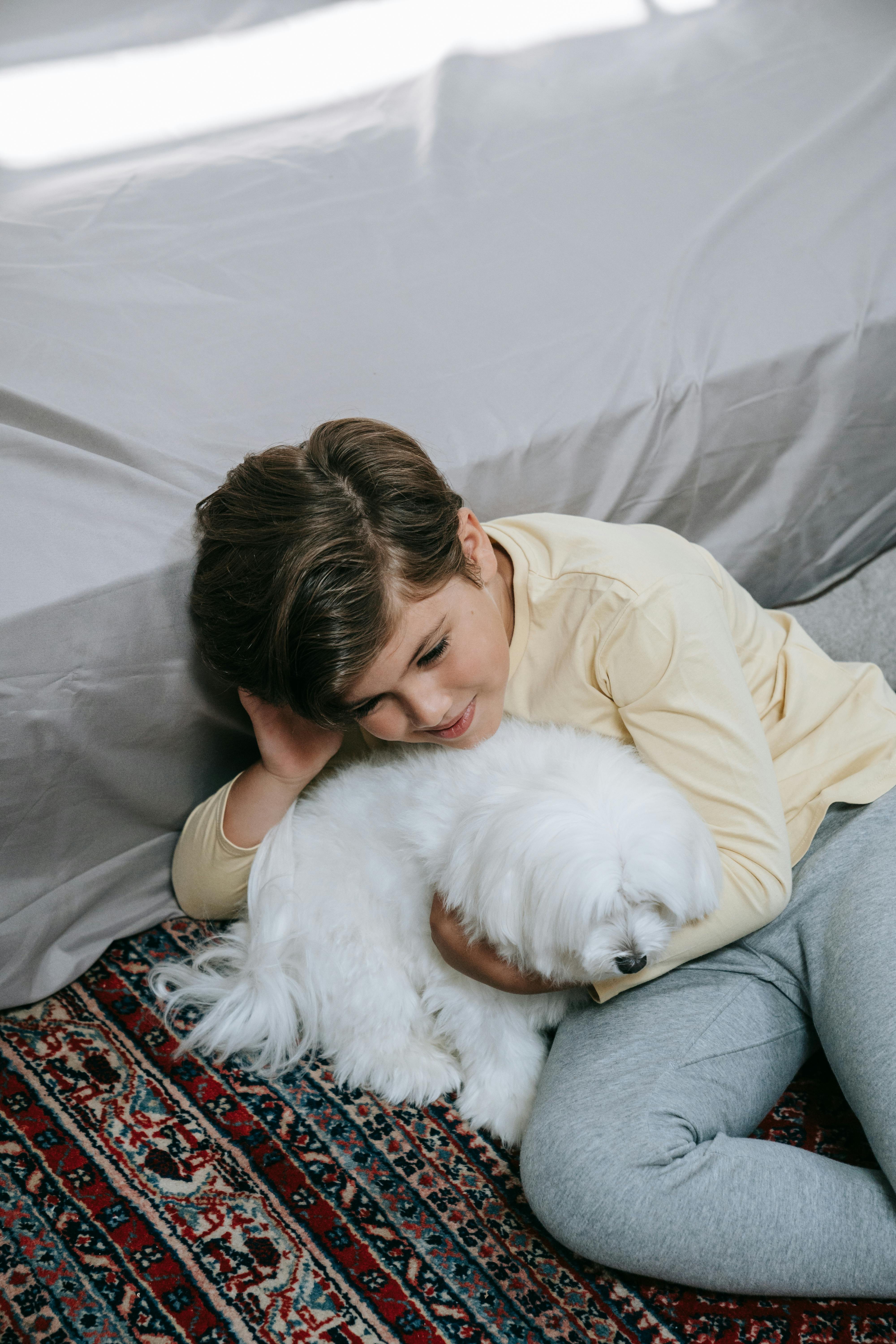 Boy Cuddling Fluffy White Dog