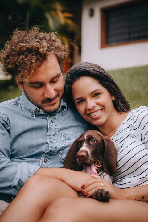 Couple Relaxing With Pet Dog Outdoors