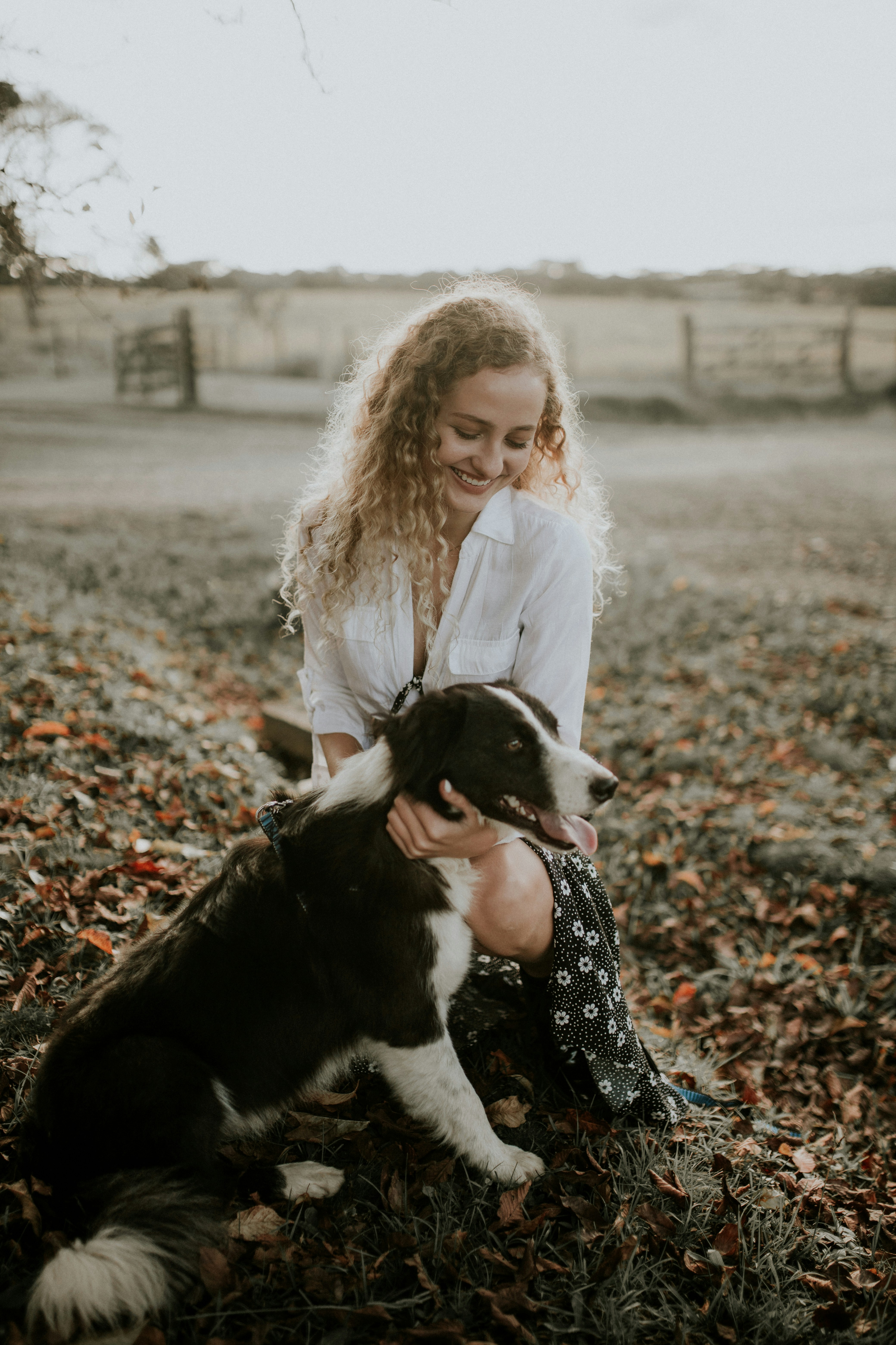 Woman Crouching With Dog In Autumn Field