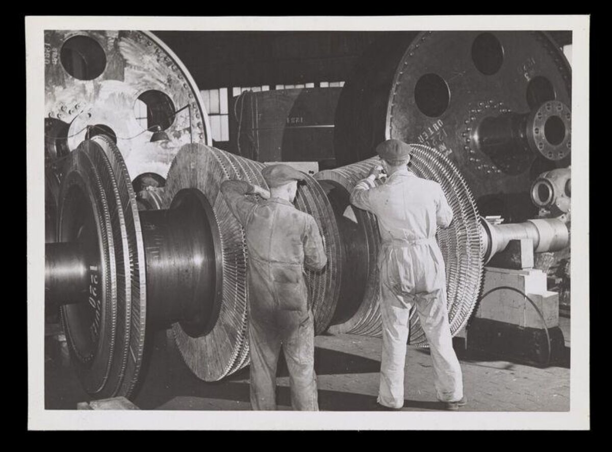Two Workers Assembling Large Turbine in Factory