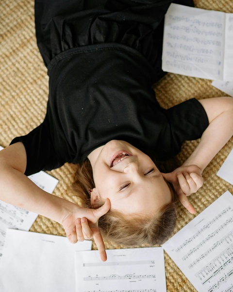 Smiling Girl Lying Among Sheet Music