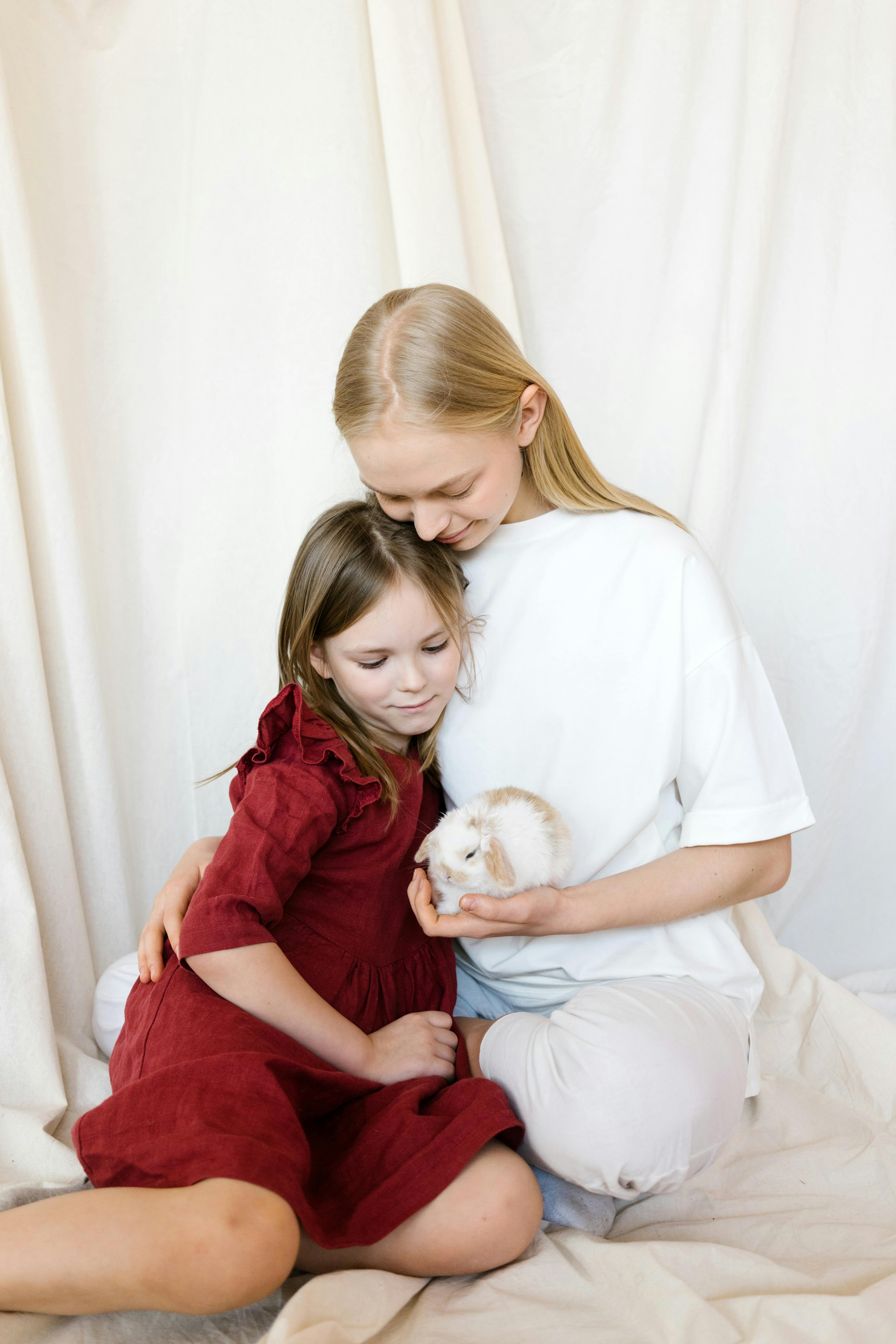 Two Girls Cuddling a Baby Bunny