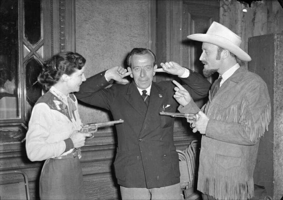 Cowgirl and Cowboy Aim at Suited Man