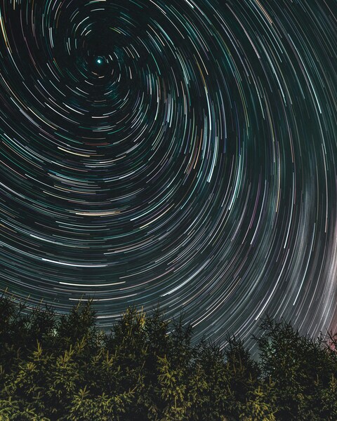 Spiral Star Trails Over Forest