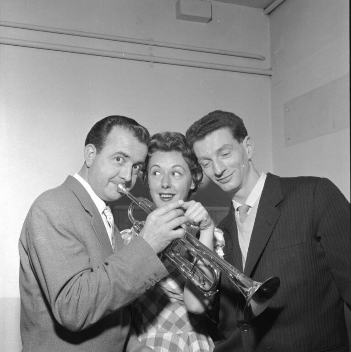 Three People Posing With A Trumpet