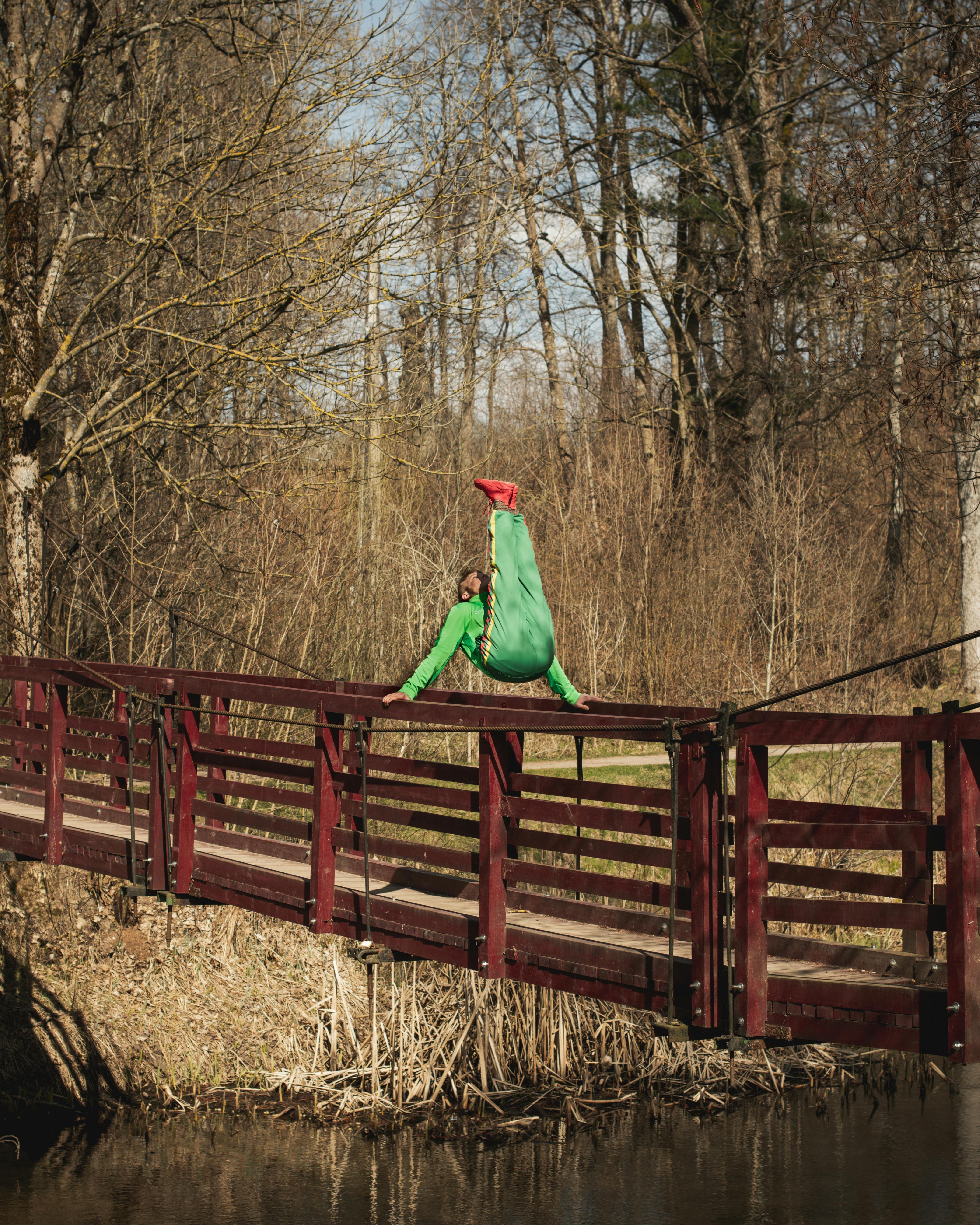 Acrobatic Pose on Red Wooden Bridge