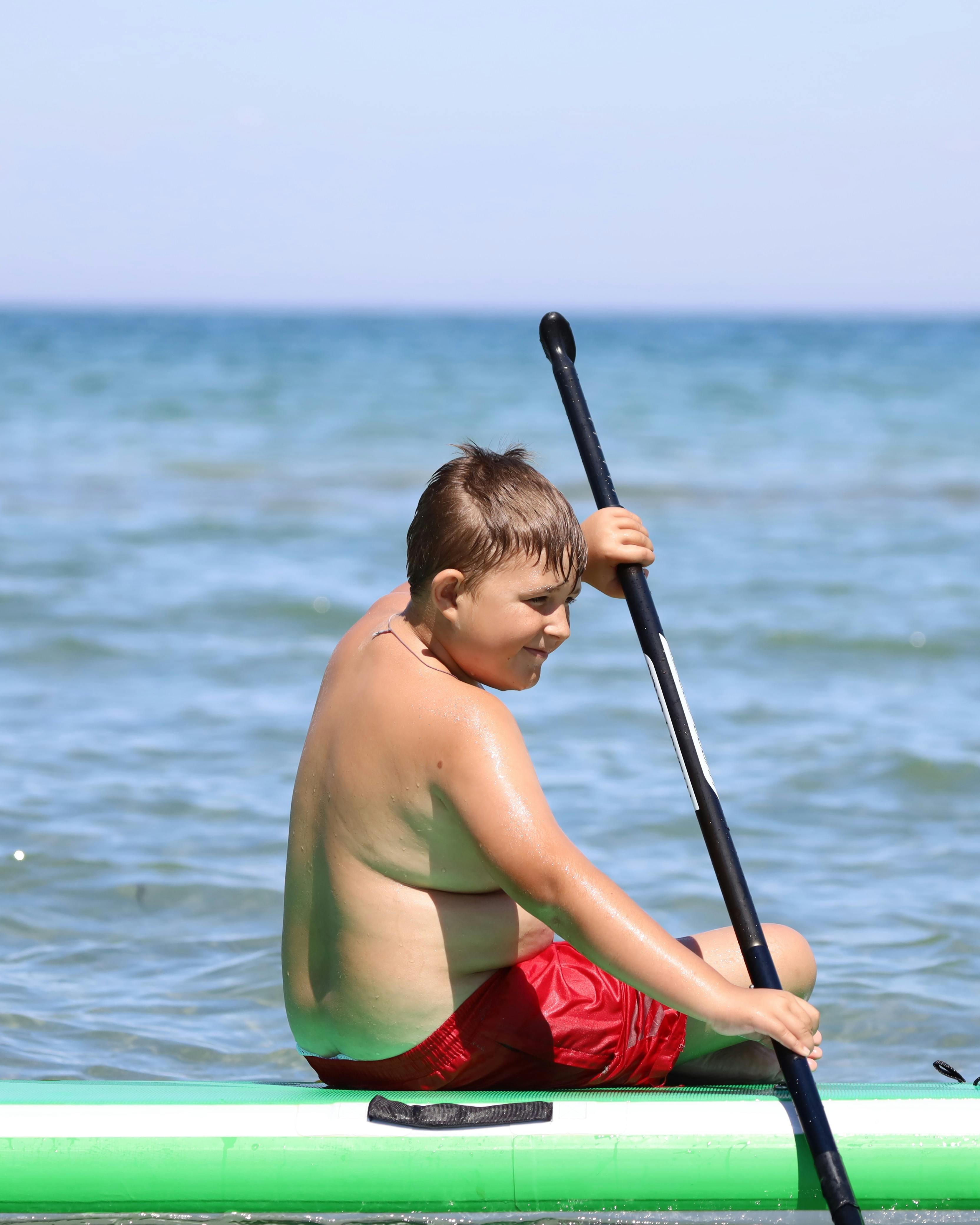 Boy Paddling on Paddleboard at Sea