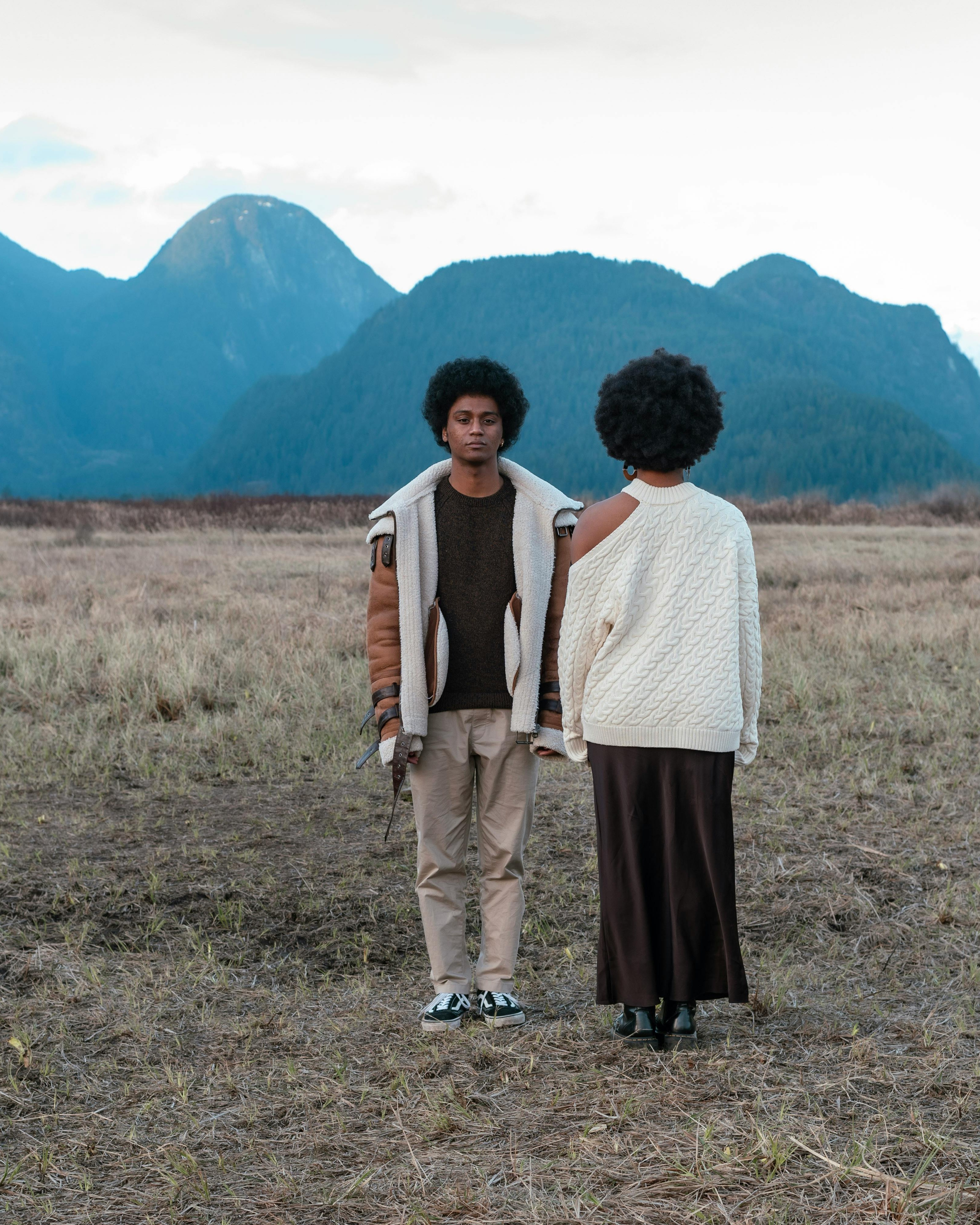 Two People in Open Field with Mountains