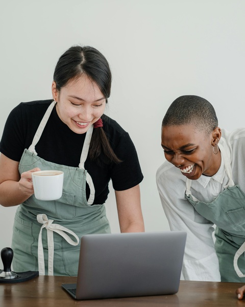 Two Cafe Workers Laughing at Laptop