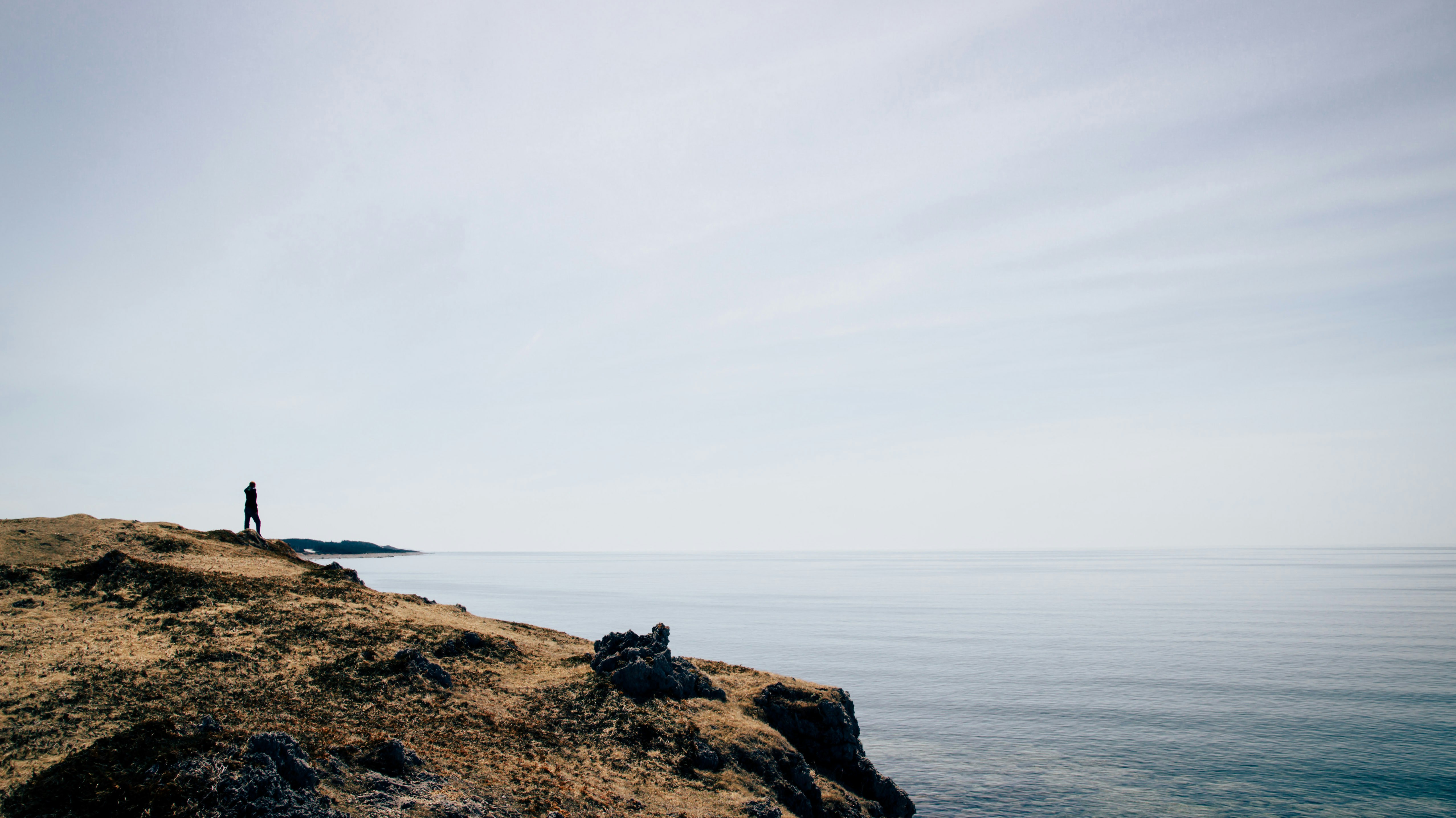 Lone Figure Overlooking Sea from Coastal Cliff