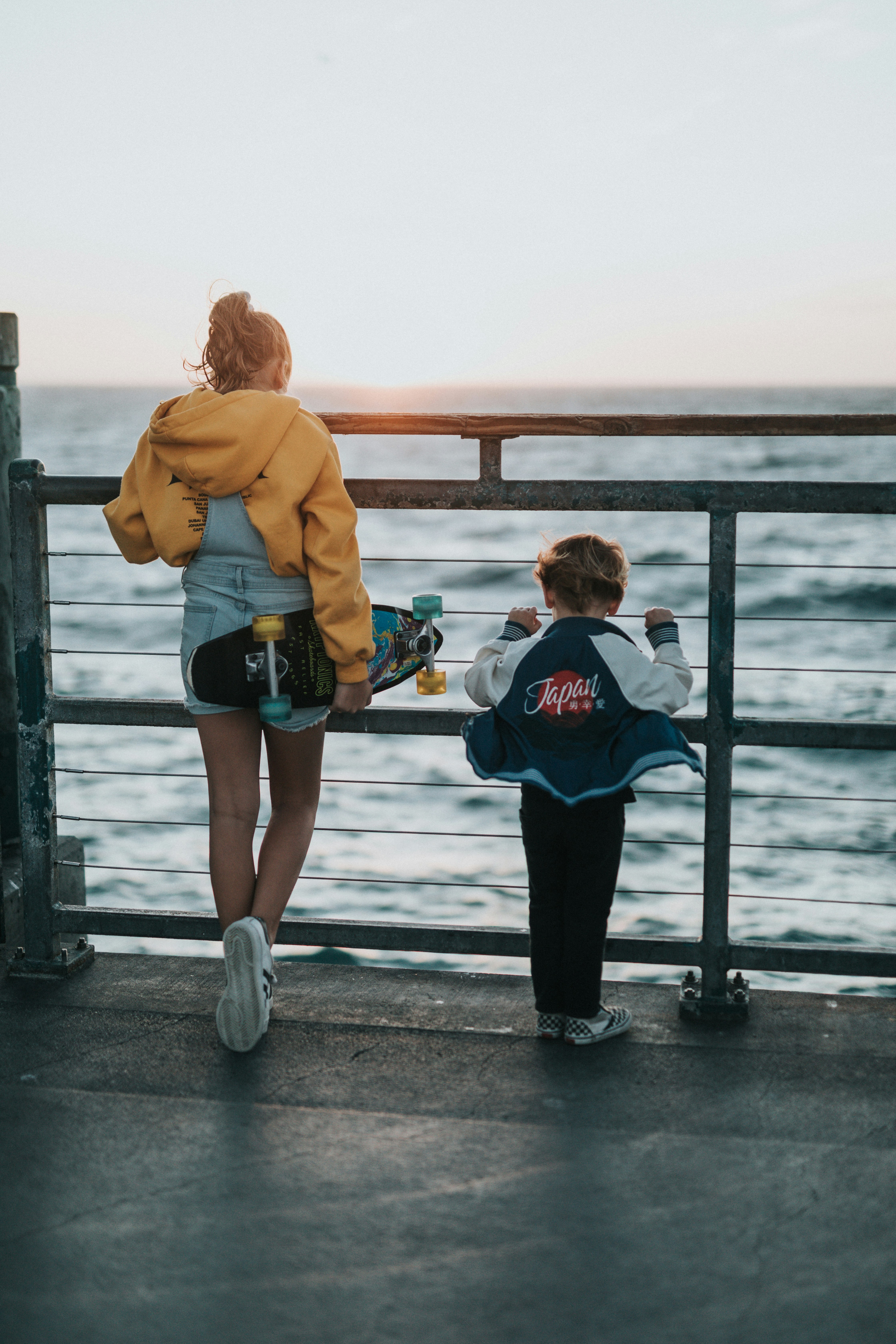Two Kids Watching Sunset on Seaside Pier