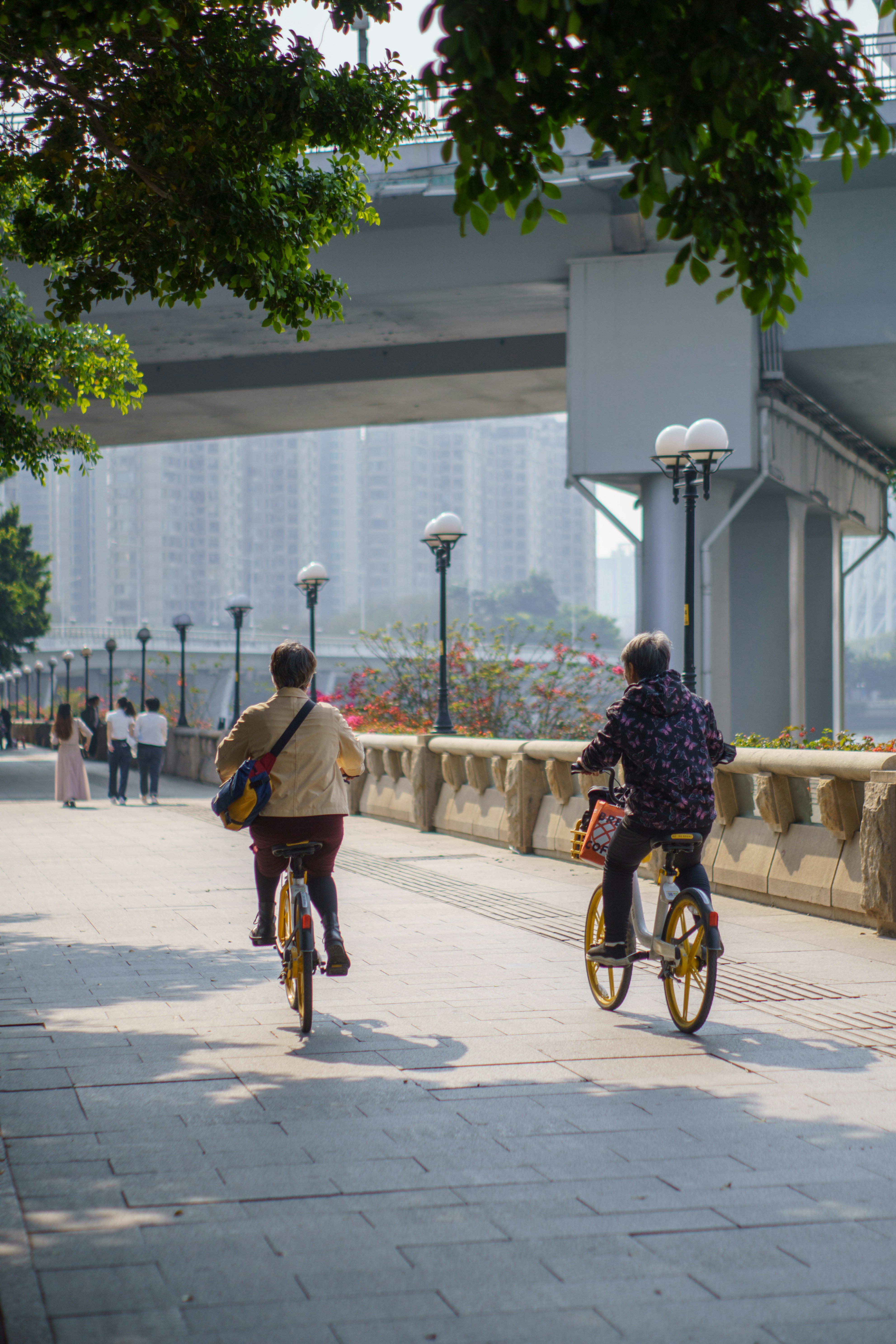 Two People Cycling on Riverside Path