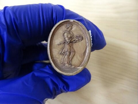 Gloved Hand Holding Carved Cameo Artifact