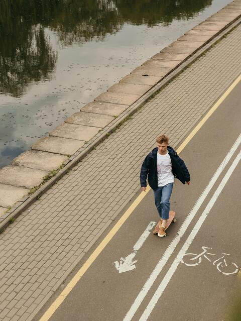 Man Skateboarding On Riverside Bike Path