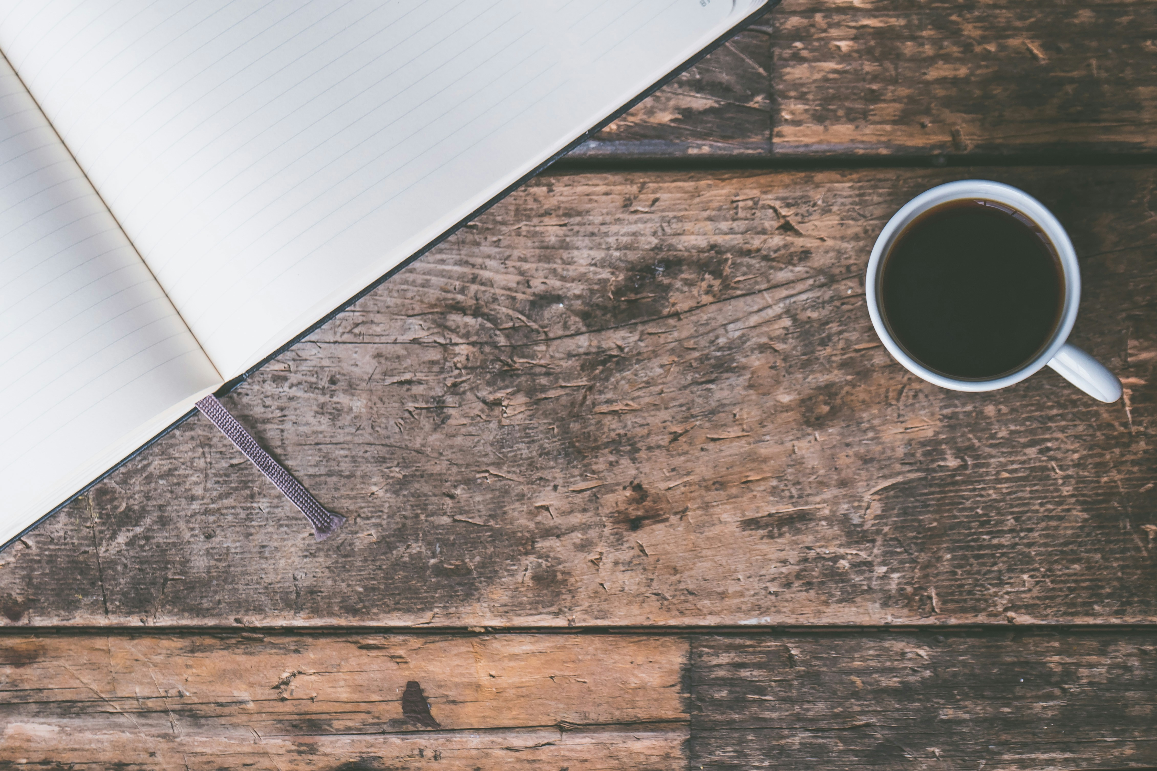 Open Notebook and Black Coffee on Wooden Table