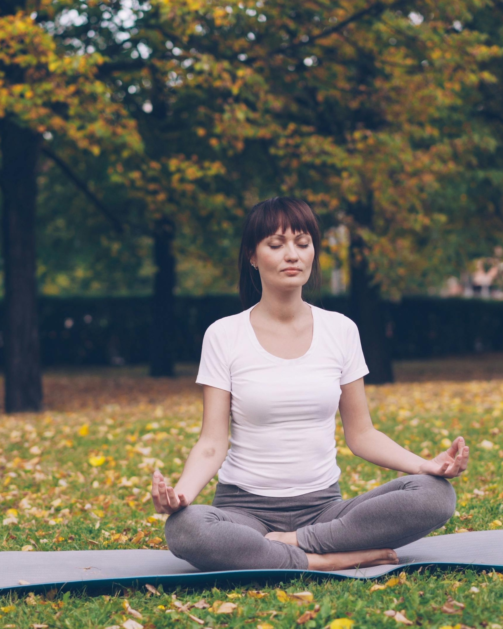 Woman Meditating in Autumn Park