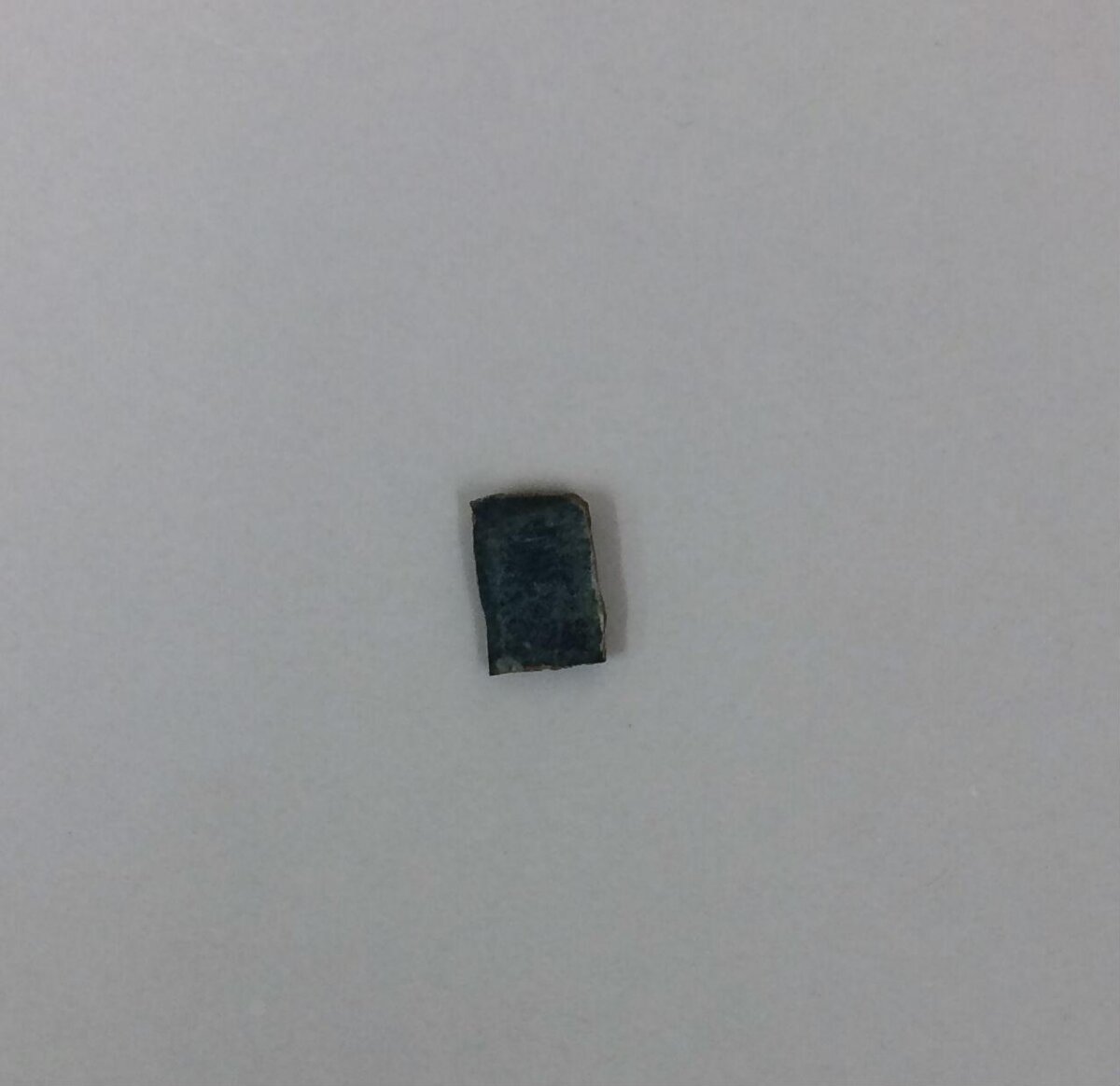 Small Dark Rock Fragment on Gray Background