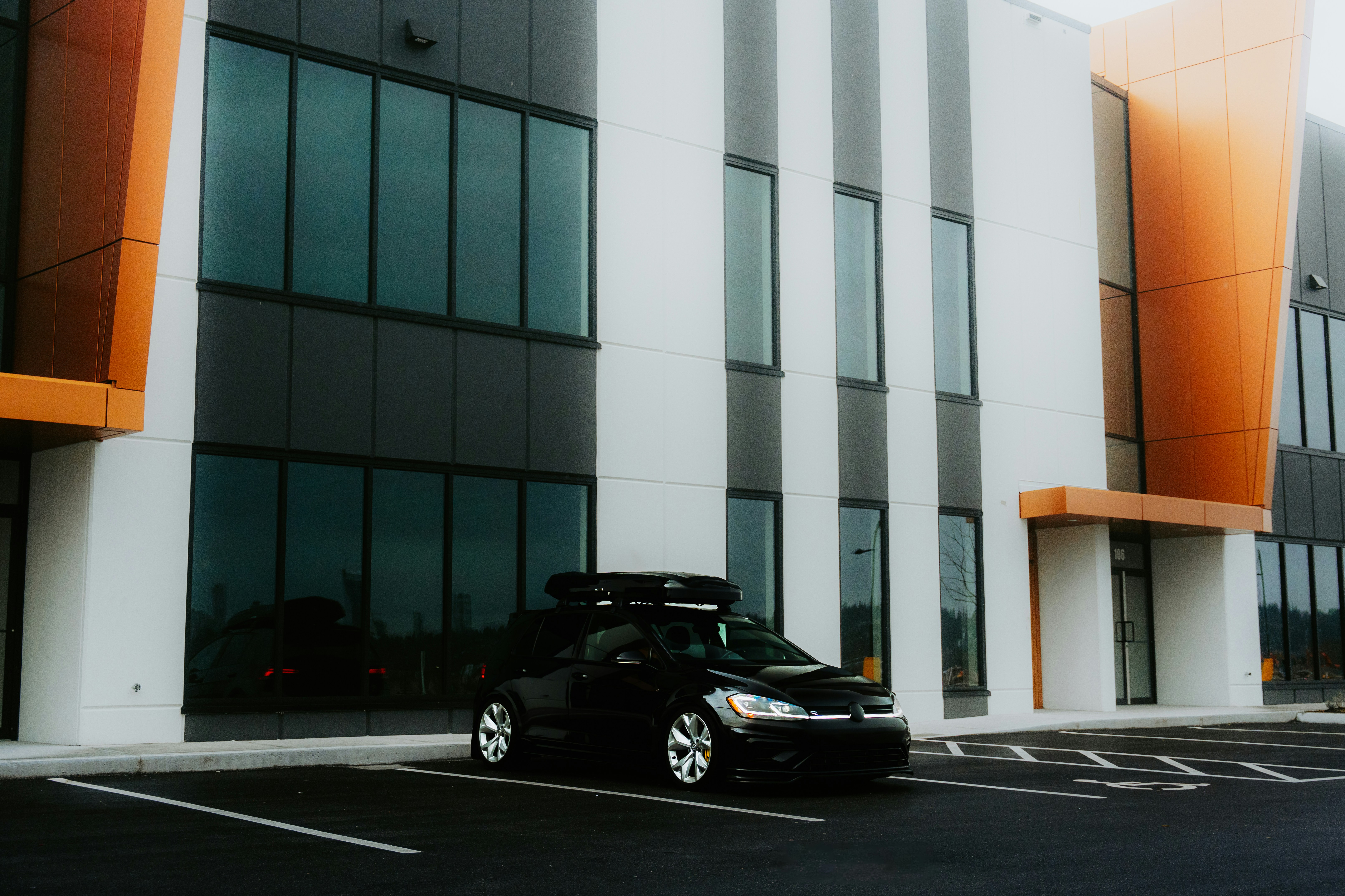 Black Hatchback Parked Outside Modern Building — Cars