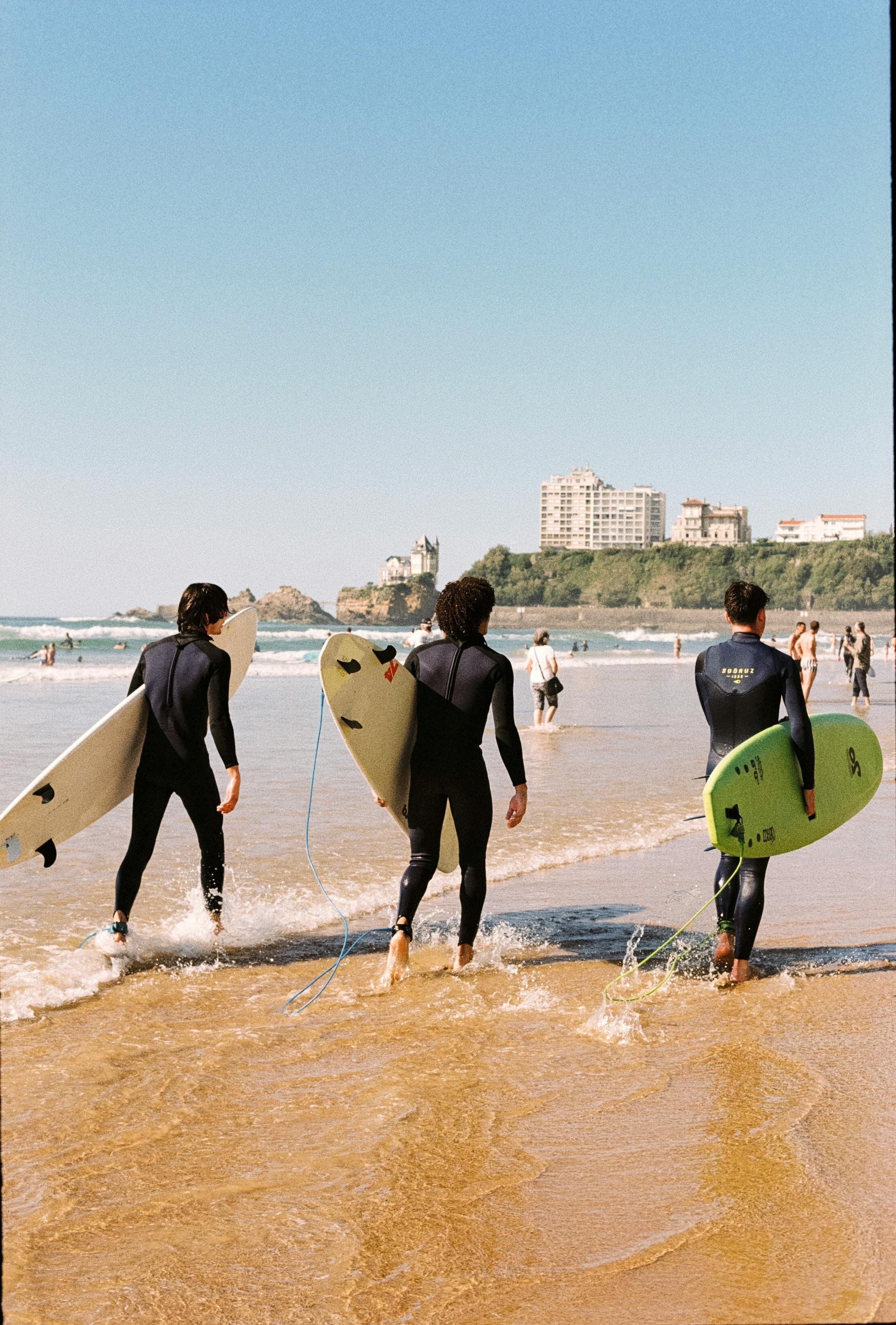 Three Surfers Walking Into Ocean at Beach