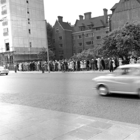 Crowd Waiting Along Urban Street