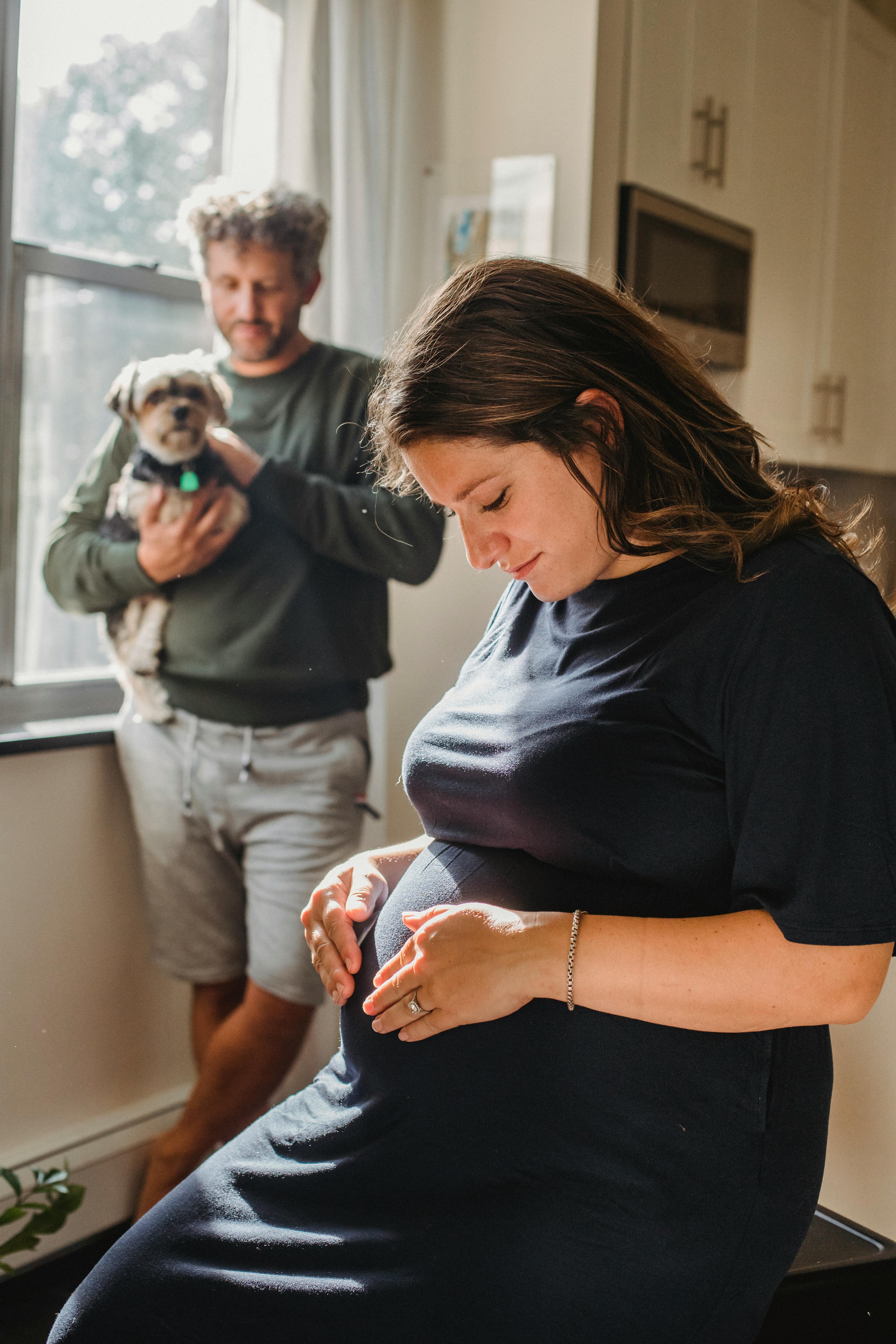 Pregnant Woman With Partner and Pet Dog At Home