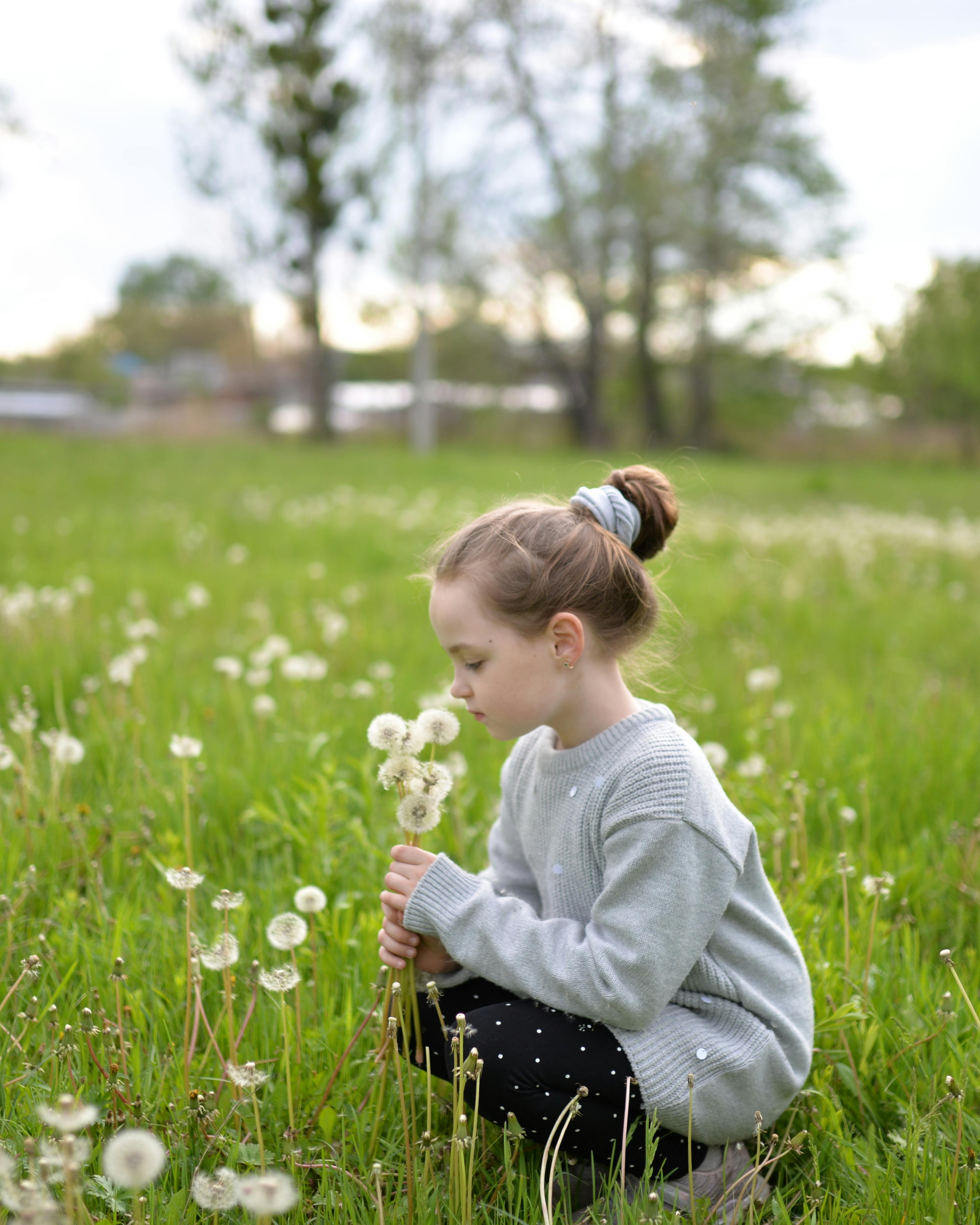 Girl Holding Dandelions in Green Meadow