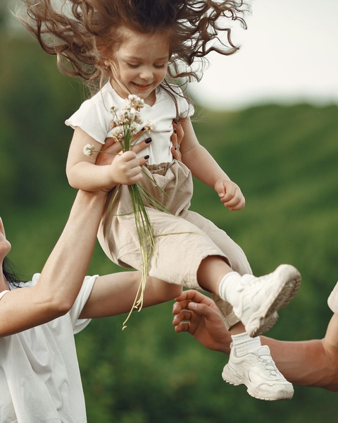 Parents Lifting Little Girl Outdoors