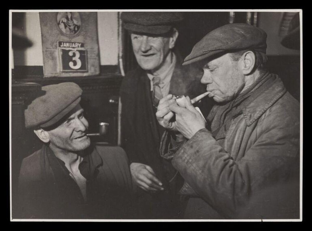 Three Working Men Lighting a Pipe